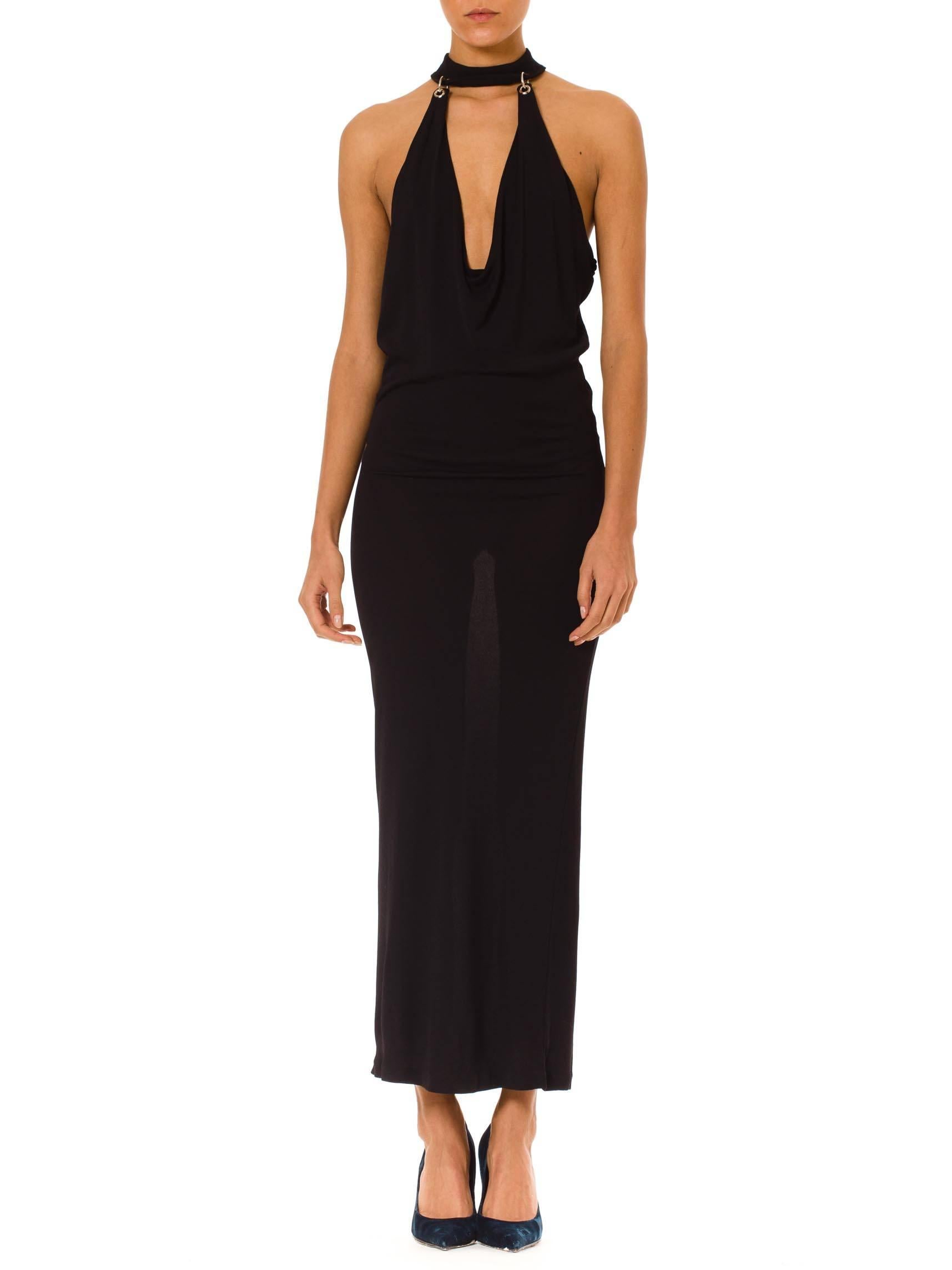 This is a stunningly sexy gown by French designer Paco Rabanne. The gown is deceptively simple, with a body-conscious silhouette, ankle-length hem, and matte black fabric. The vamp-factor comes from the incredible neckline and body revealing cut.