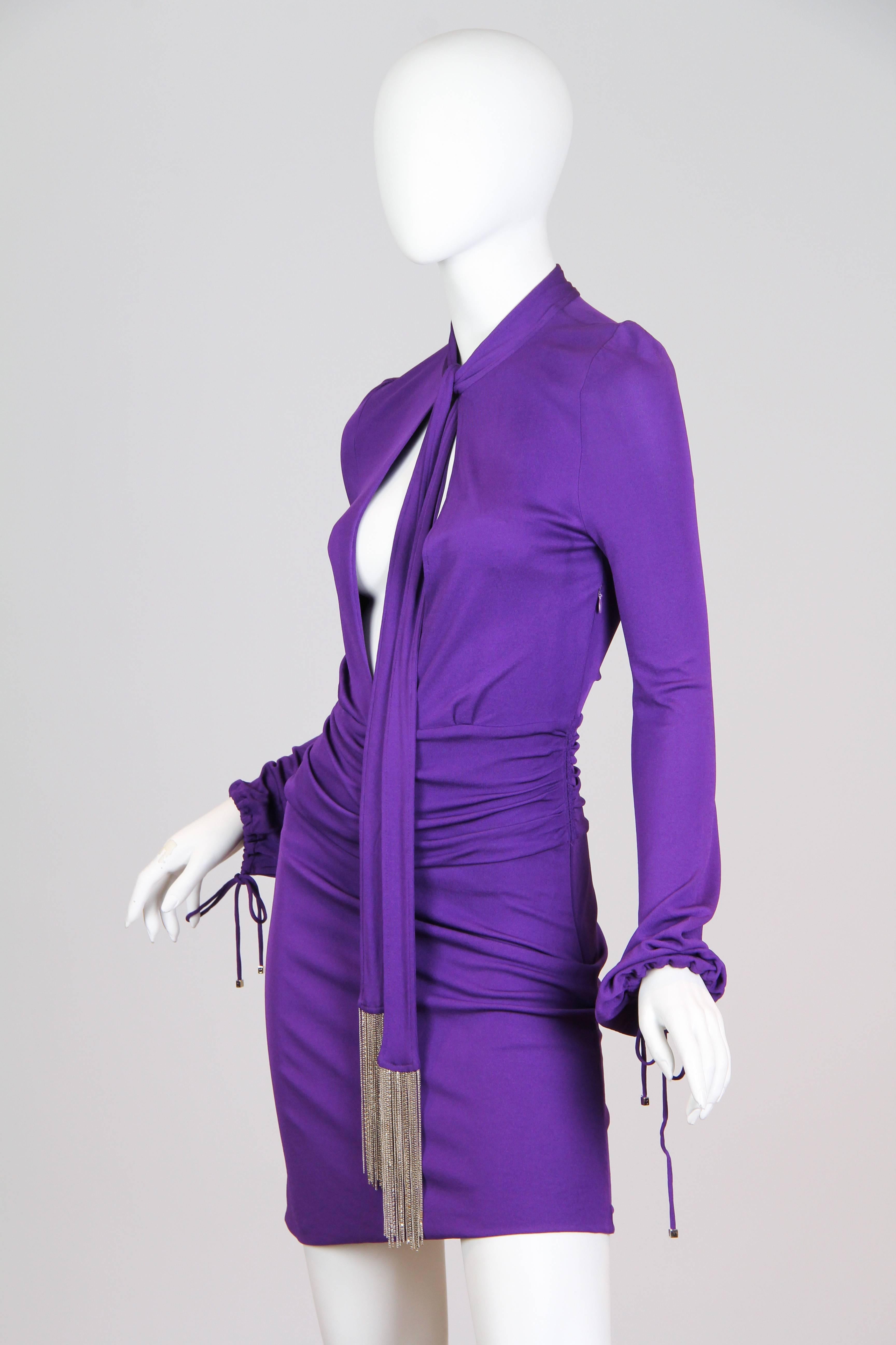 This is a purple jersey-knit dress by famed design house Gucci, dating from the Tom Ford 1990s. The body-conscious shape is accented by ruching across the mid-section for a flattering silhouette, and the long sleeves balance the deep neckline