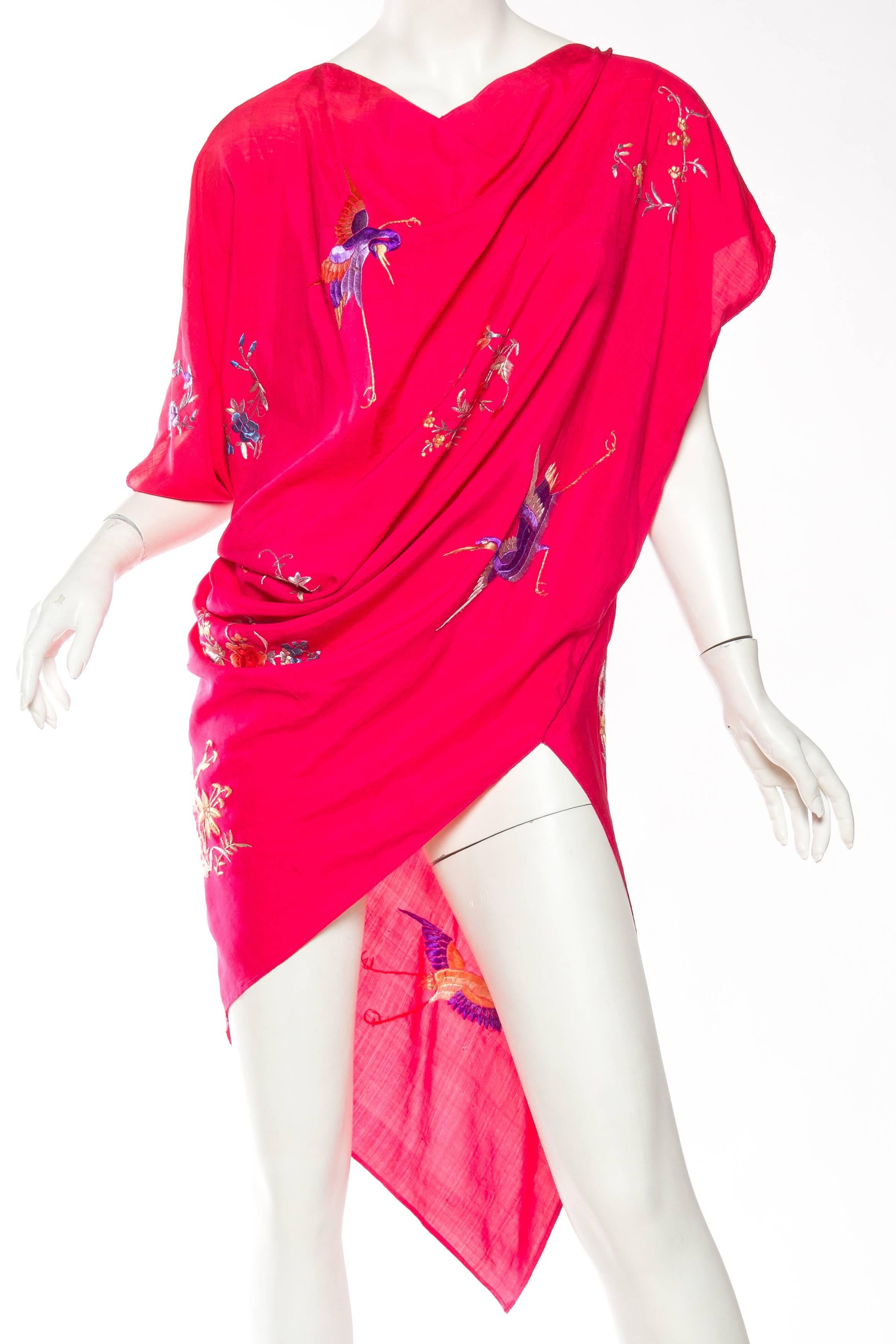 This is a wonderful tunic from the 1940s, constructed of fabric made in India or China. Made of an incredible lightweight silk in the brightest fuschia hue, it is embroidered all over with flowers and birds in shades of amethyst, green, gold, blue,