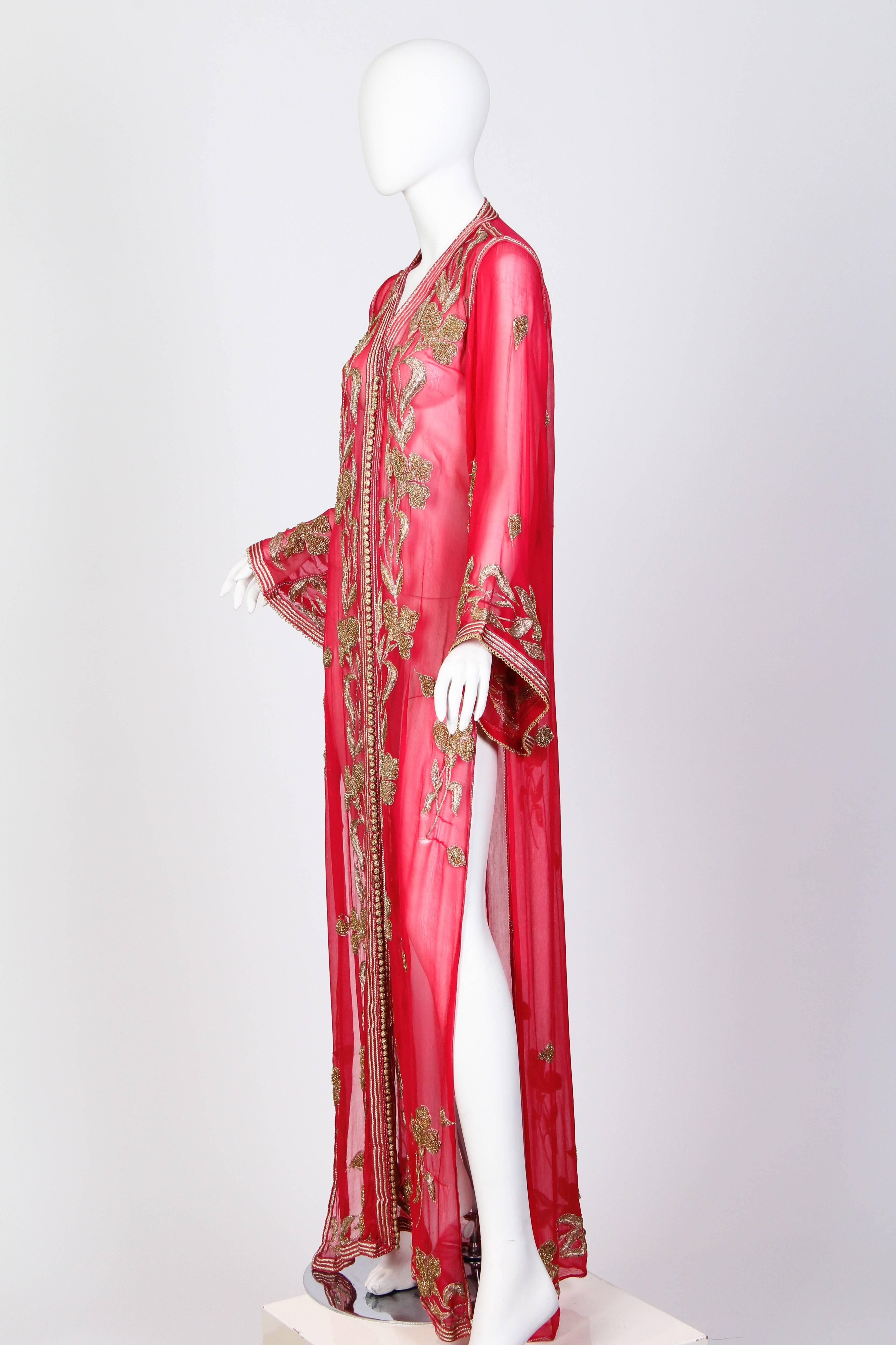 This is an ankle-length red chiffon tunic, embroidered with stunning floral motifs. The tunic falls to the floor in the front and back, and is slit all the way up to the hips on both sides. It opens up the center front with a myriad of little gold