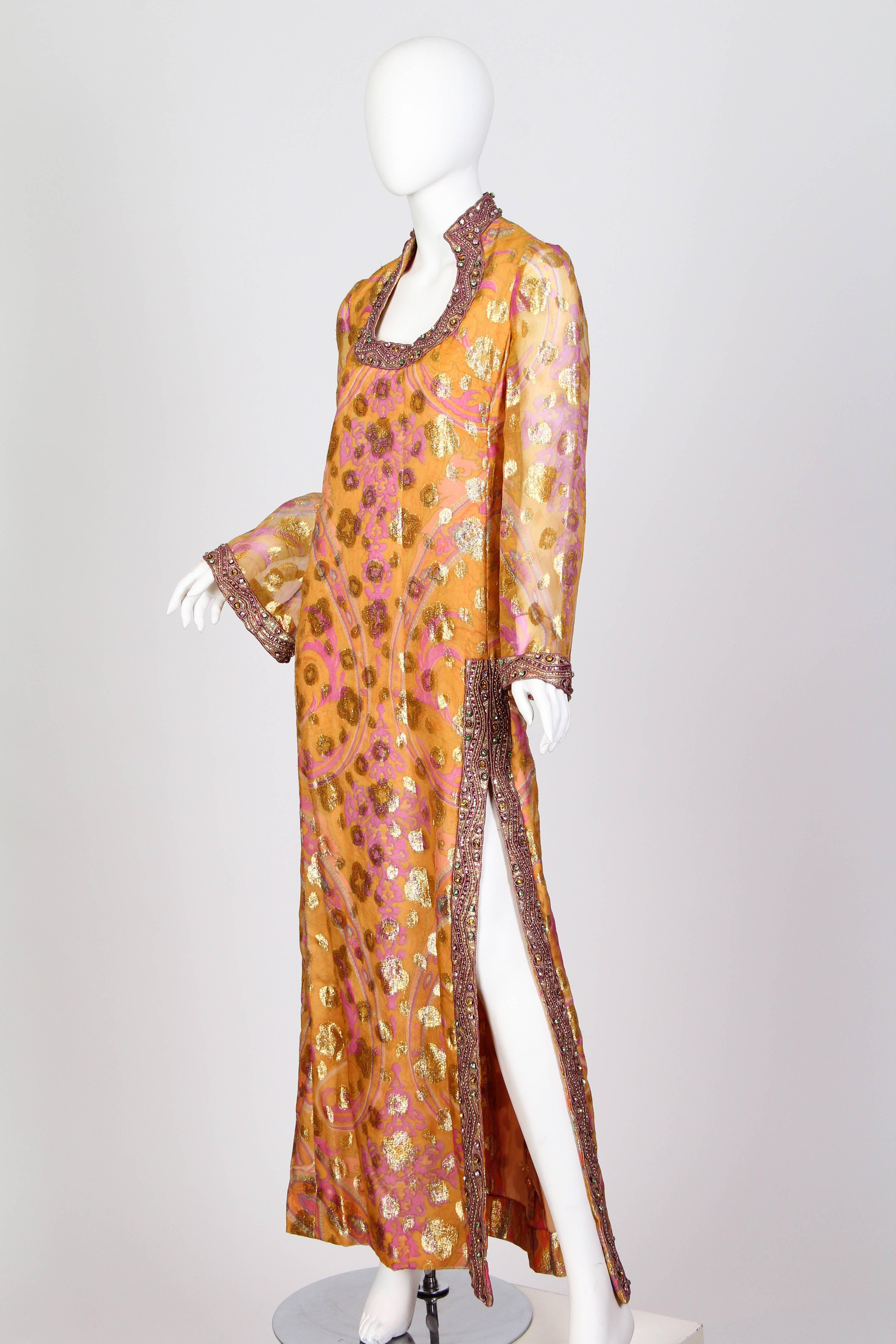 Fantastic luxe lurex organza has been printed with the patterns of the east in the colours of the sun. The stratigic slit and unique collar have been heavily embroidered in gold passimentrie which swirls around an array of large crystals. The long