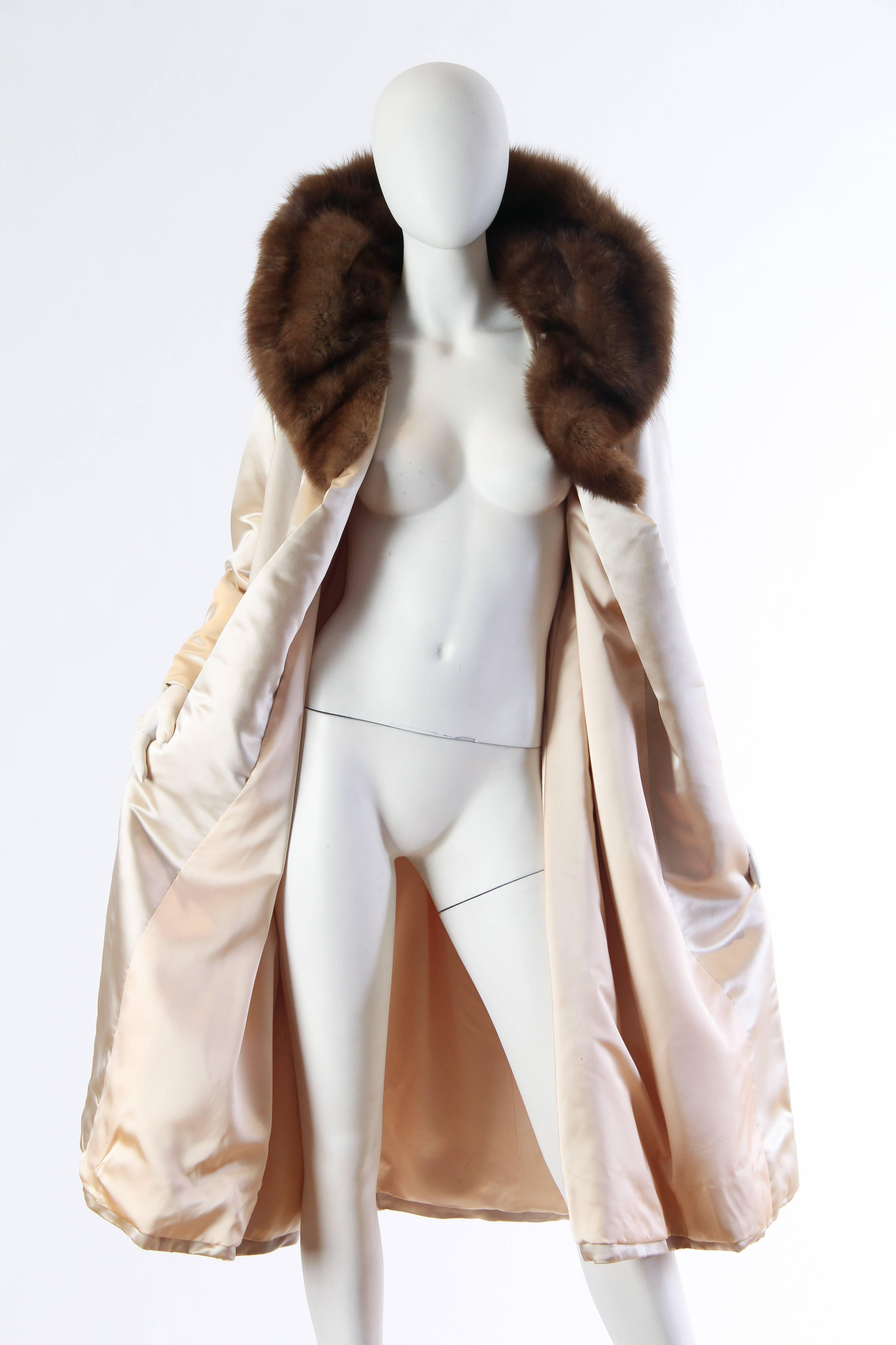 Luxuriously heavy duchess satin constructs this classic mid-century opera coat from New York retailer Bergdorf Goodman. A simple yet wonderful collar of sable frames the face and folds up for warmth. There is no closure as the coat is meant as a