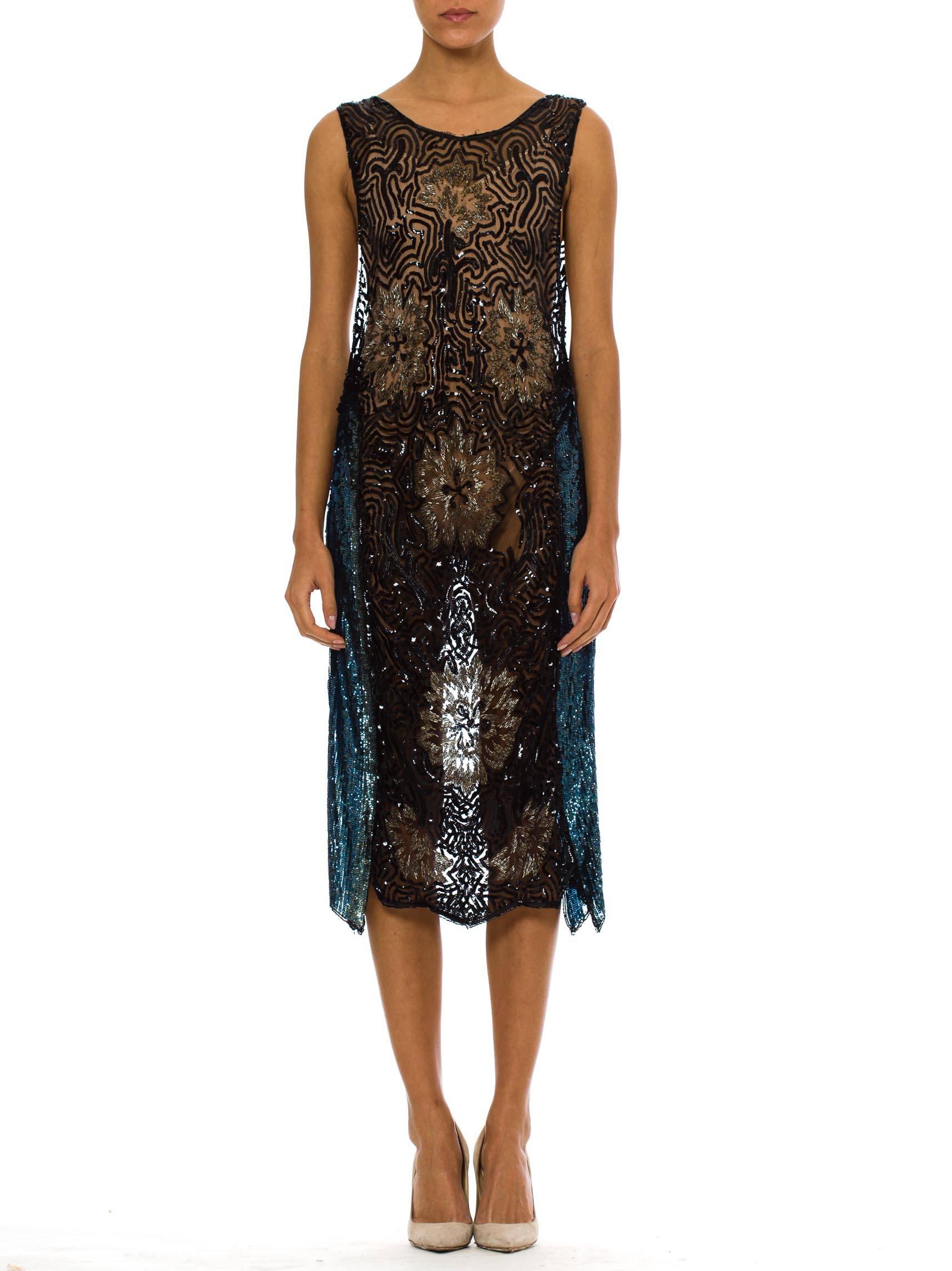 This is a stunning beaded and sequined overdress of sheer panels, with open sides.  Seven large flowers are arranged on the front in silver beadwork, with abstract black sequins filling in the background. Striking sky blue panels of solid