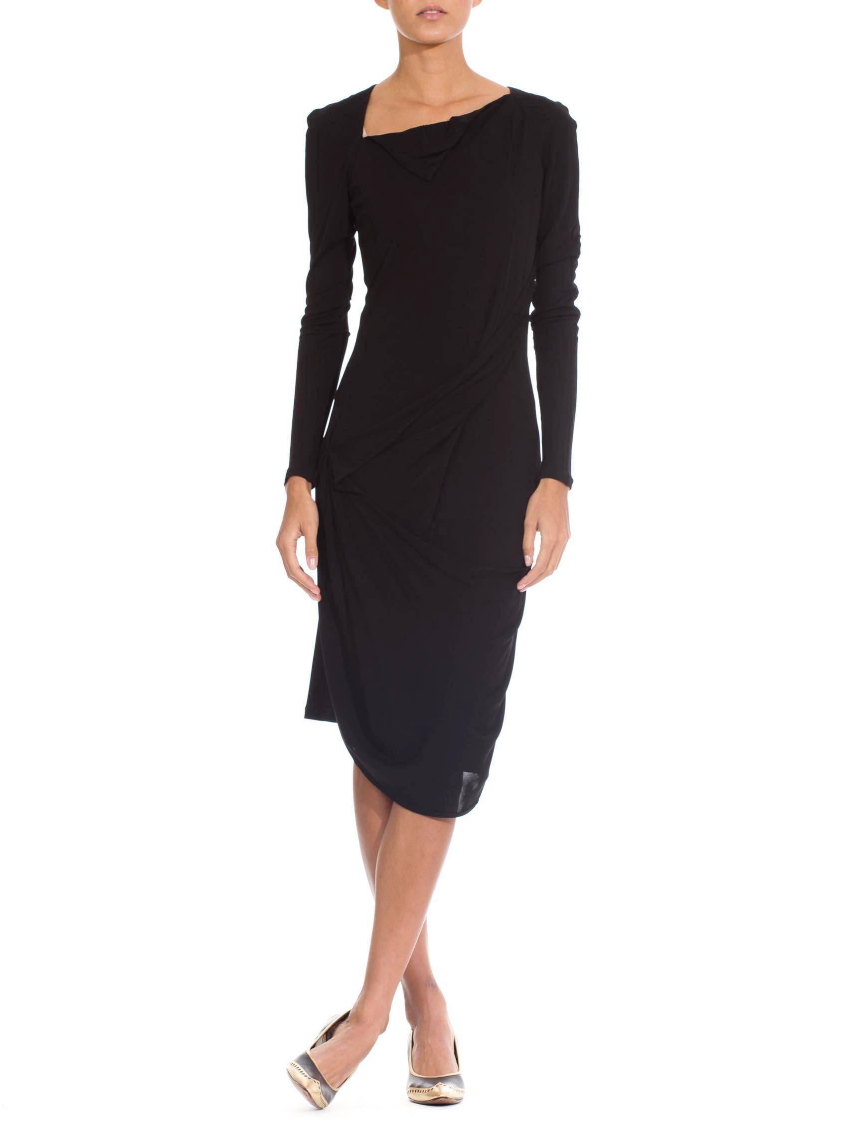This is a beautiful Little Black Dress from the house of Martin Margiela. Classic and simple, it is made elegant by the delicate draping of fabric diagonally across the body. The folds run from the upper ribs across to the hip, and from there sweep