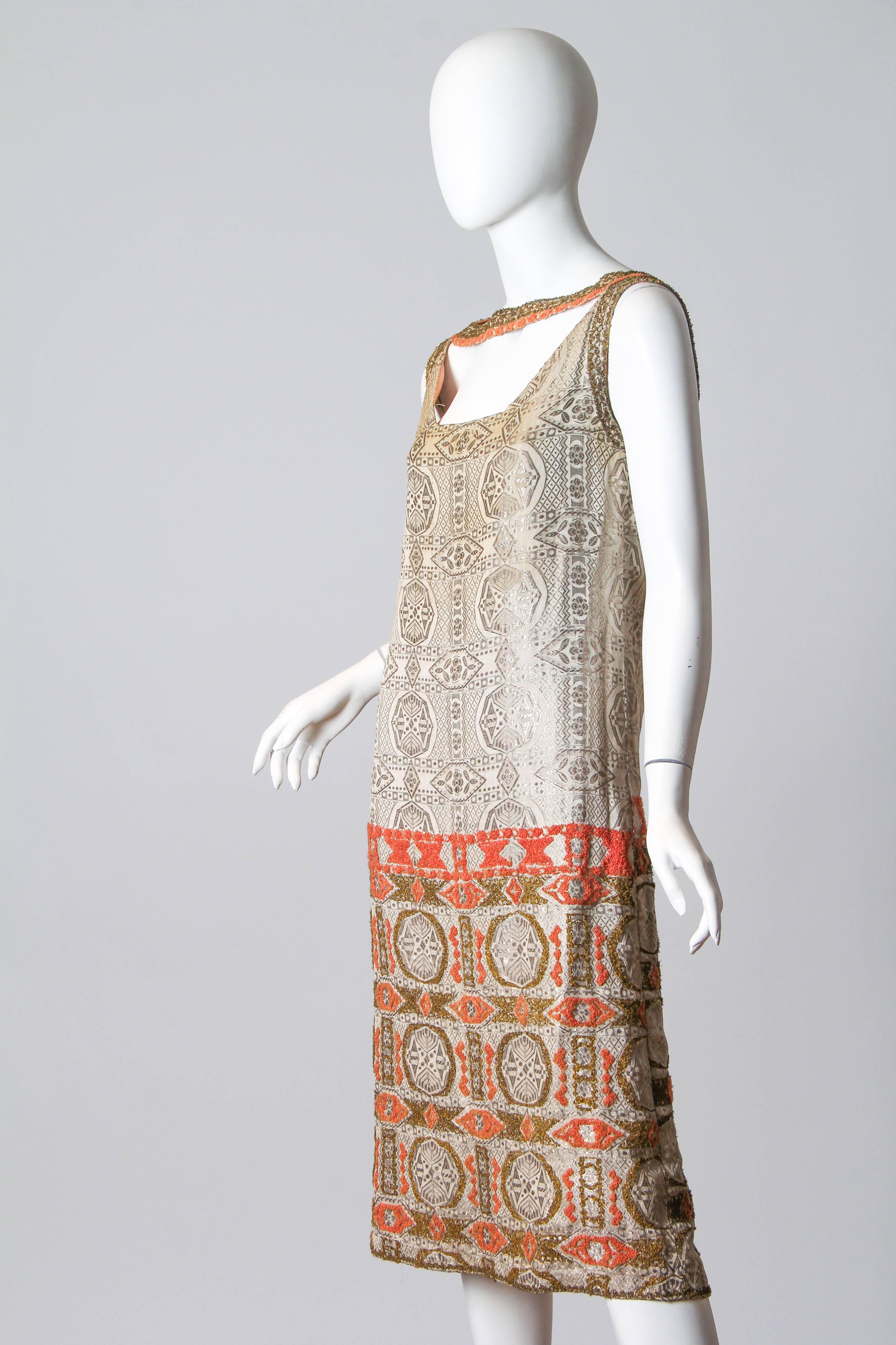 An interesting artistic and yet risqué dress from the flapper age. Purchased in Paris we couldn't resist the individuality of this very high quality dress. The silver lamé jacquard of this dress has been hand embroidered with metal and silk