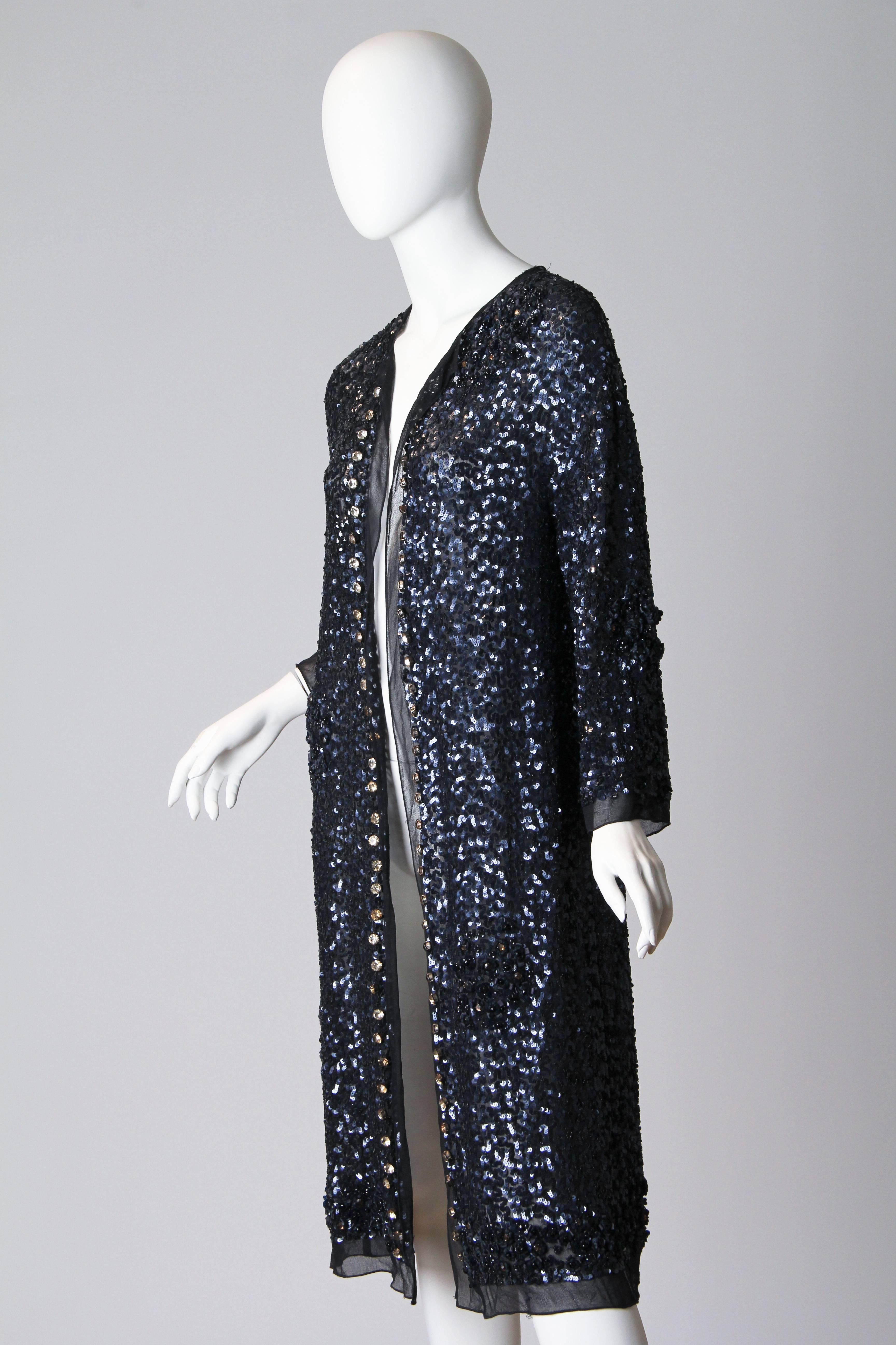Effortless to wear with loads of glamour we love this beaded jacket. The construction is simple, a single piece of chiffon. The work complex, the entire piece has not only been covered in navy blue sequins, there are also several clusters of flowers
