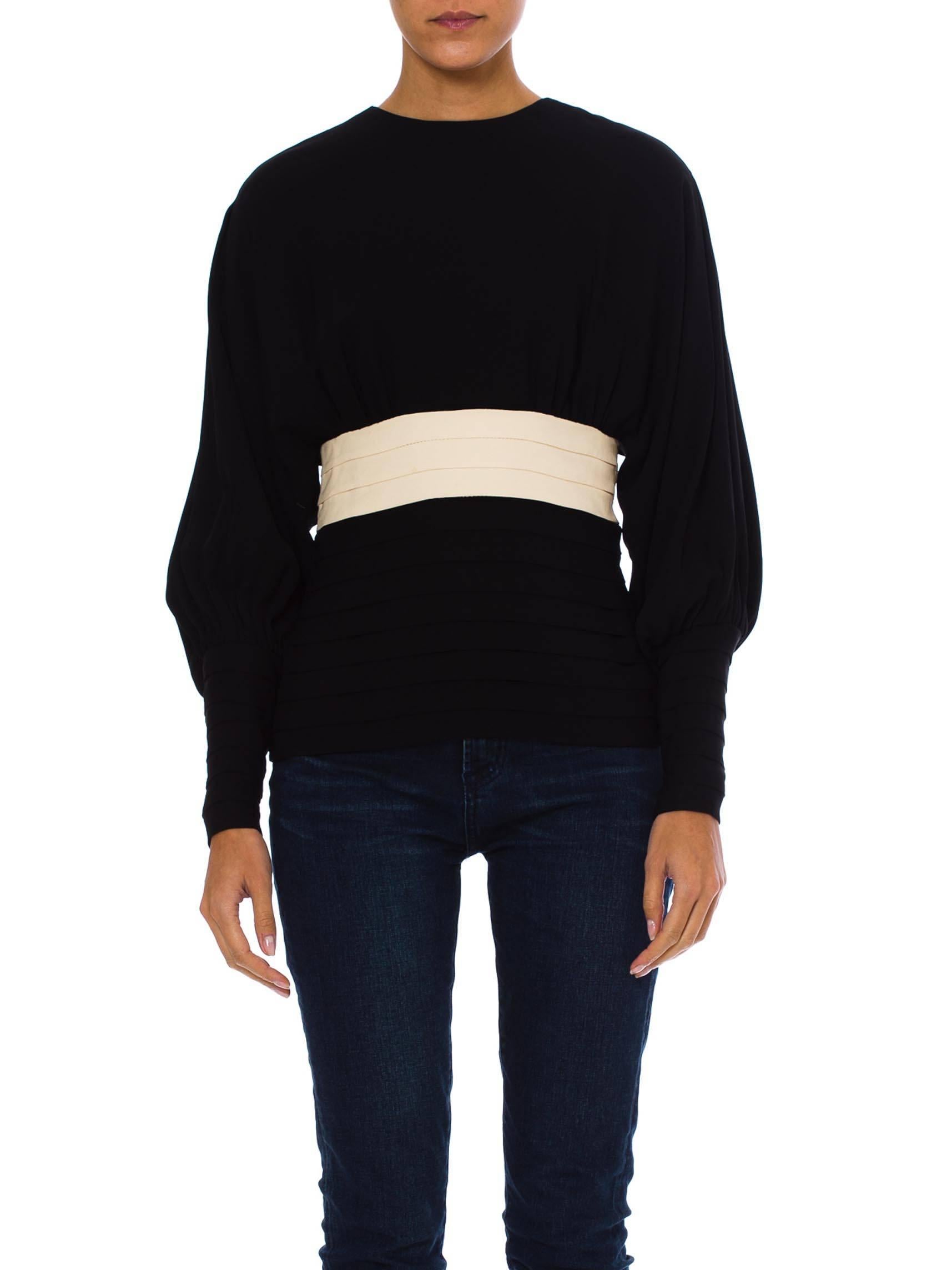 This is a striking colour-blocked black and white top. The top is fitted through the hips and waist, with even knife-pleated tucks giving texture to the hip panel. A pleated white panel defines the waist and underbust for a very flattering effect.