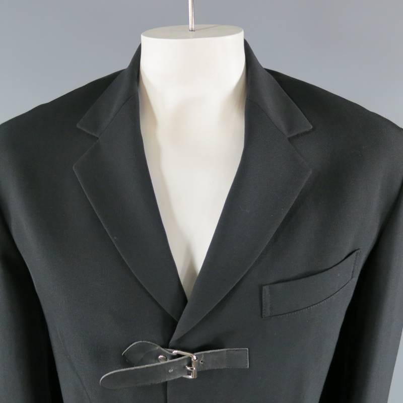 YOHJI YAMAMOTO Sport Coat consists of 100% wool material in a black color tone. Designed with a notch lapel collar, 3 leather belt closure with silver buckle, top pocket square seam and 2-bottom flap pockets with tone-on-tone stitching accents.