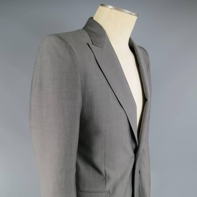 Alexander McQueen Sport Coat consists of wool/ mohair material in a grey color tone. Designed with a slim peak lapel collar, single button front, front mid-section tone-on-tone stitching. Detailed with 2-bottom flap pockets, 4-button cuff sleeves,