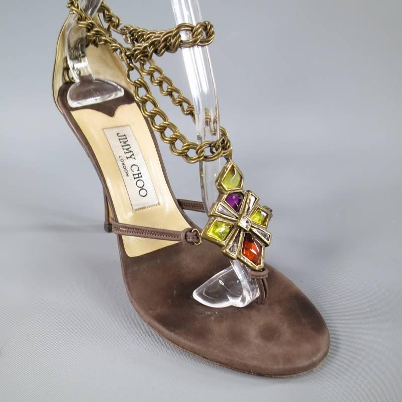 These gorgeous JIMMY CHOO sandals come in a toupe brown nubuch suede and feature a stiletto heel, and a chain strap with gothic gold tone brass gemstone cross. Made in Italy.

Excellent Pre-Owned Condition.	Marked: 37.5

Heel: 4 in.
Width: 3.5