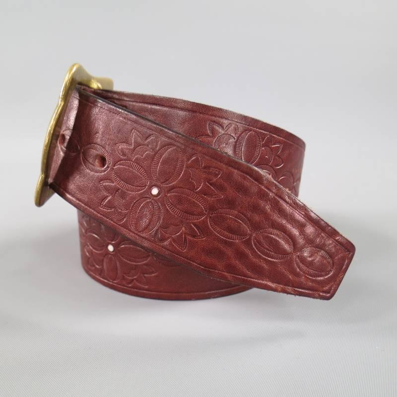 DSQUARED2 Brass Buckle Belt consists of a burgundy embossed leather material with solid brass gold tone buckle. Designed with a floral embossed pattern that can be seen throughout length of belt. White dot detailing can be seen towards midsection of
