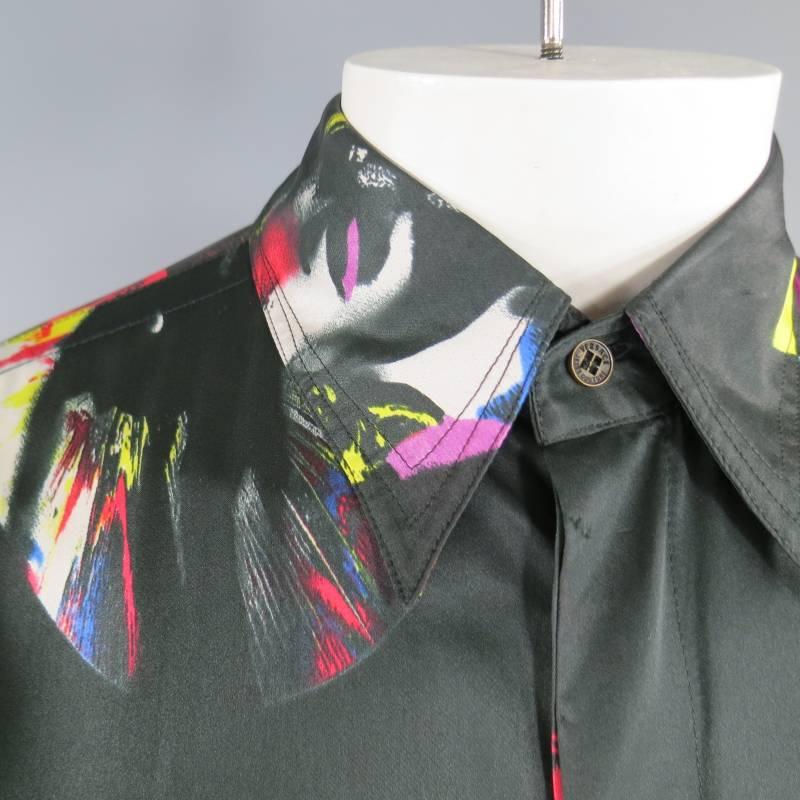 This rare and unworn GIANNI VERSACE JEANS COUTURE shirt comes in a black silk / viscose blend satin and features a pointed collar, hidden placket, and all over abstract rock n roll new wave print of lips, records, and faces. Made in Italy.
 
Brand