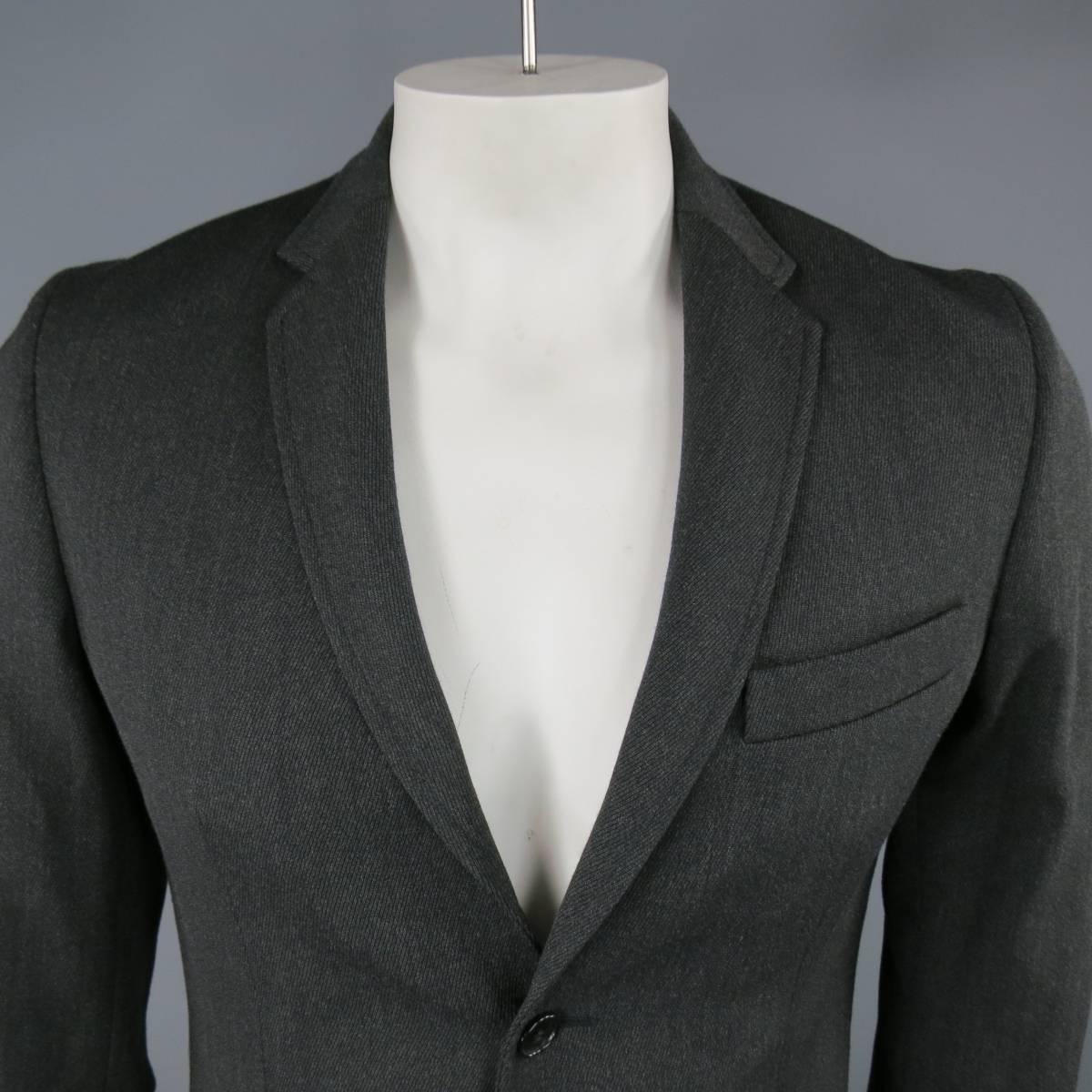 MAISON MARTIN MARGIELA Sport Coat consists of 100% wool material in a charcoal color tone. Designed with a notch lapel collar, 3-button front, bottom flap pockets and top pocket square. 4-button cuffs, single back vent with full construction lining.