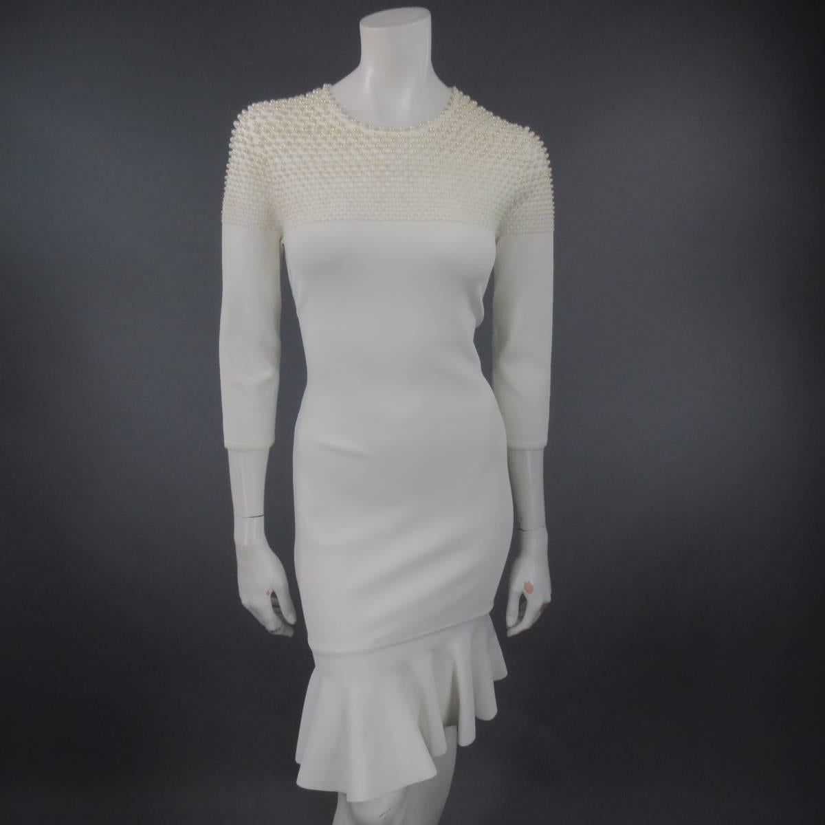 Gorgeous bodycon dress by ALEXANDER MCQUEEN. A fitted 3/4 sleeve crew neck style in cream stretch knit, embellished with faux pearls that cascade from large to small along the top and finished with a ruffle hem on the skirt. Elegant enough to dress