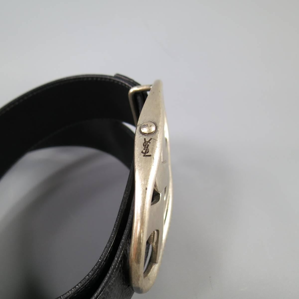 This classic YVES SAINT LAURENT belt comes in black pebbled leather and features adjustable button stud closure and an oversized, silver tone, retro YSL logo oval buckle. Made in Italy.
 
Very Good Pre-Owned Condition.
Marked: 34
