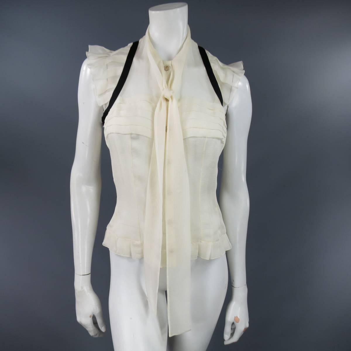 This beautiful CHANEL Fall 2006 sleeveless blouse comes in cream beige silk chiffon with a pleated chest, ruffled shoulders, black piping, gold tone sun engraved and rhinestone buttons, and round neckline with tied pussy bow. Made in France.
