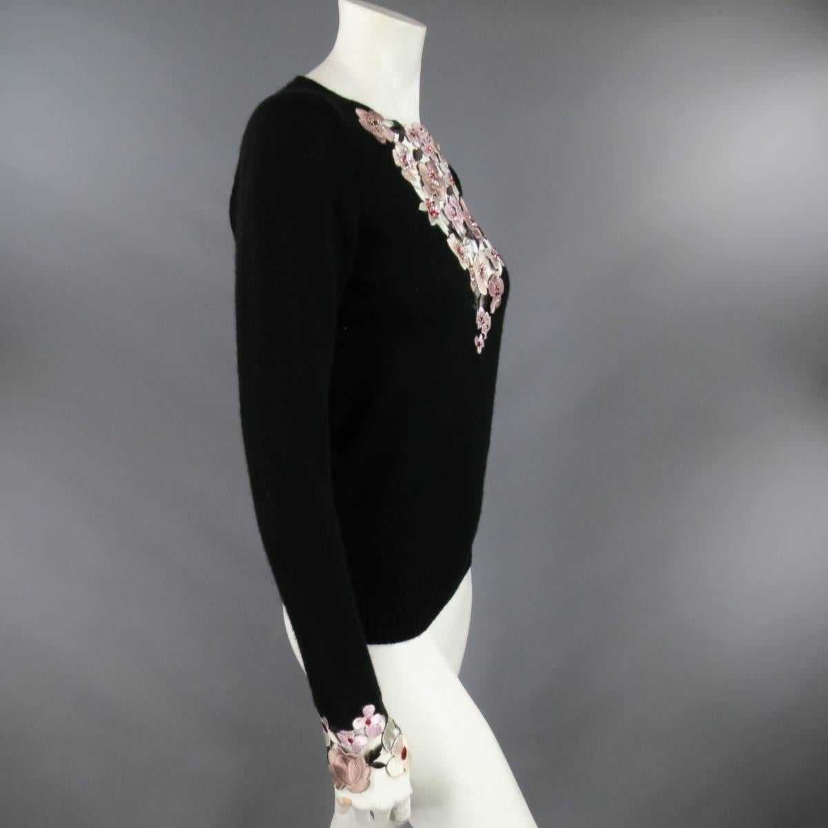 This lovely CHANEL pullover sweater comes in soft black cashmere with a deep V neck filled in with a cutout panel of champagne tone sequin embroidered flowers, embroidered floral cuffs, crystal CC embellishment, and ribbed waistband. Missing Chanel