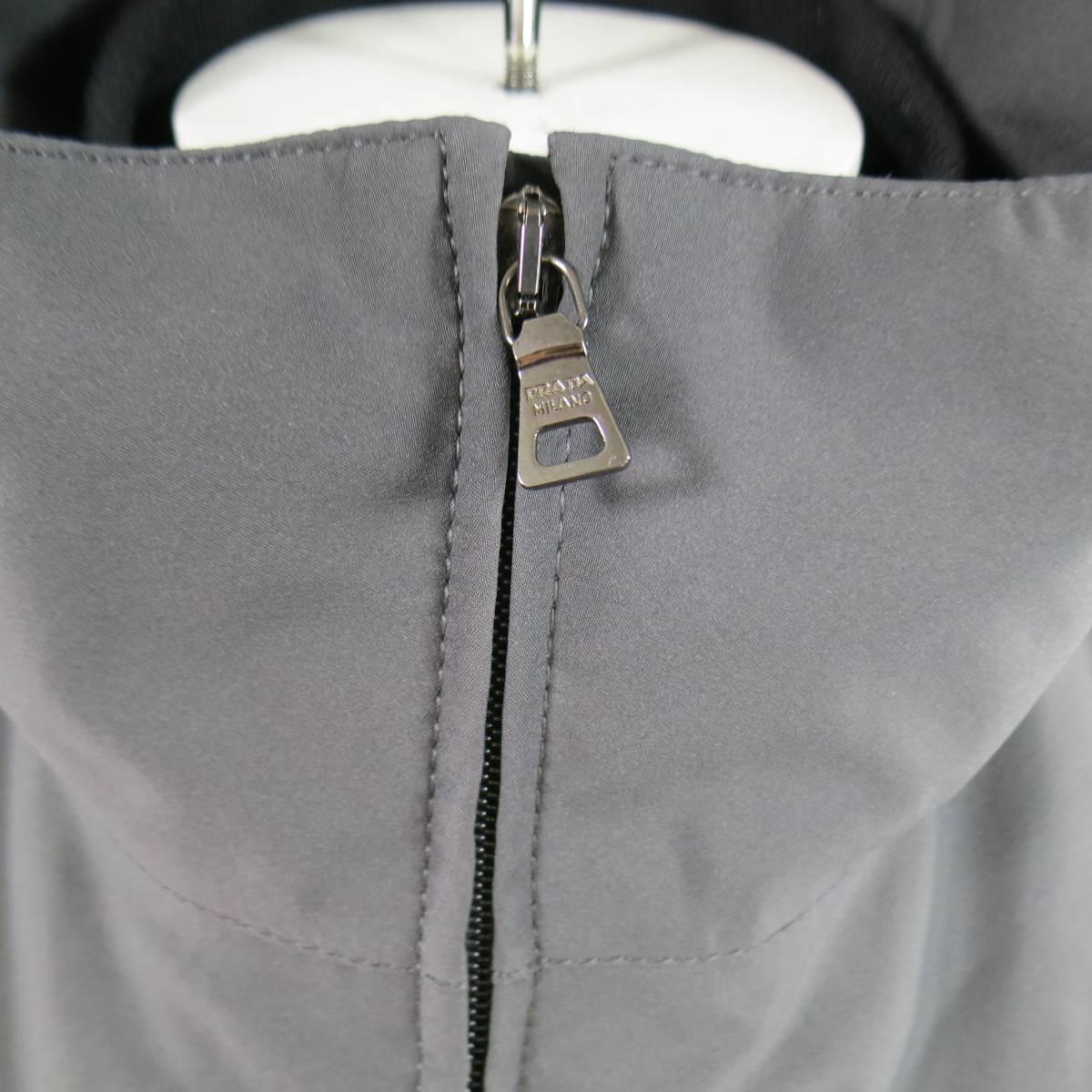 PRADA Jacket consists of nylon material in a slate color tone. Designed with a detachable double layer, zipper front closure, inseam side zipper pockets and tone-on-tone stitching along seams and velcro cuffs. Second layer comes in a polyester