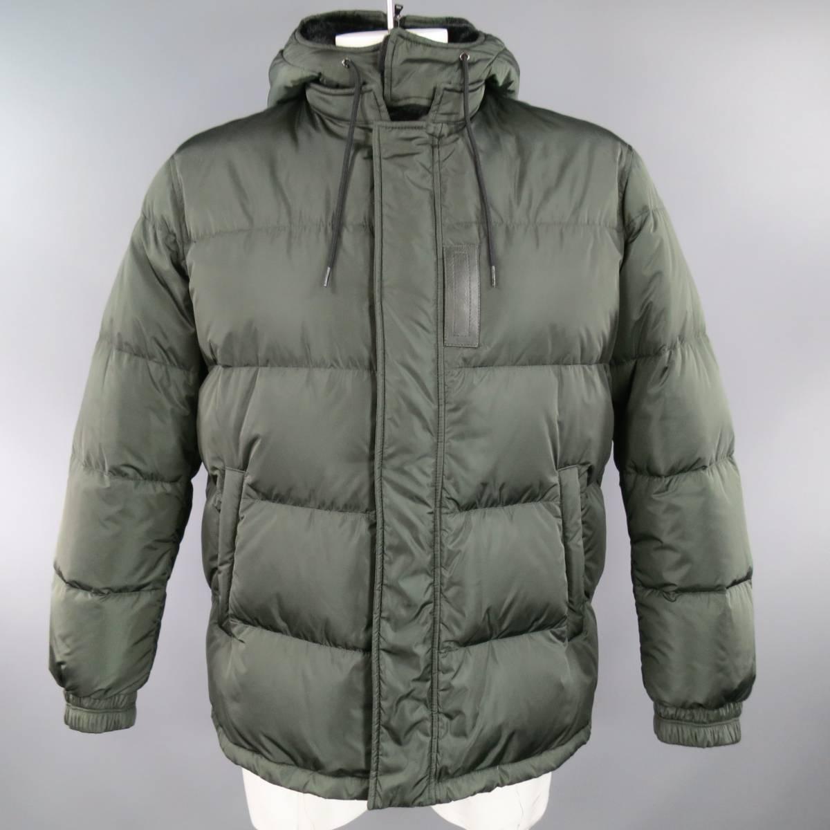 PRADA Jacket consists of poliammide material in a olive color tone. Designed with a zip-up front and snap closure, detachable hooded collar lined in a soft polyester. Zipper side pockets, black leather trim detail, quilted pattern throughout body