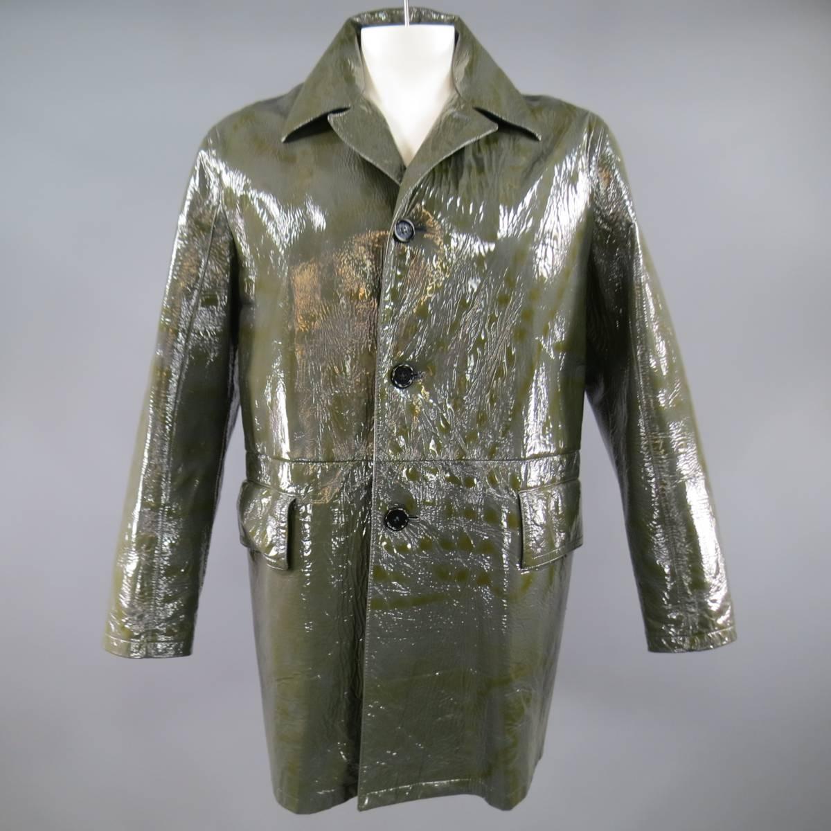 This rare PRADA classic menswear design with a twist coat comes in a glossy, high shine patent, wrinkle textured charcoal and olive green coated canvas material and features a pointed collar, four button closure, frontal flap pockets, and detachable