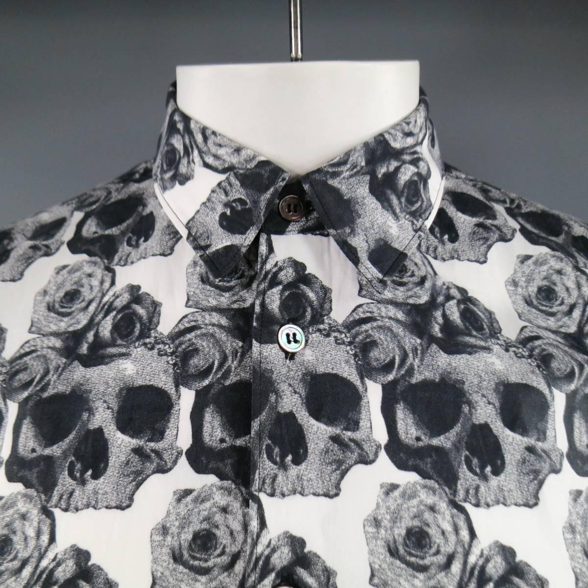 COMME des GARCONS Long Sleeve Shirt consists of cotton material in a black and white color tone. Designed with a slim pointed collar, button-up front, skull and rose print throughout body of shit. Single button cuff, 3/4 length sleeve and cropped