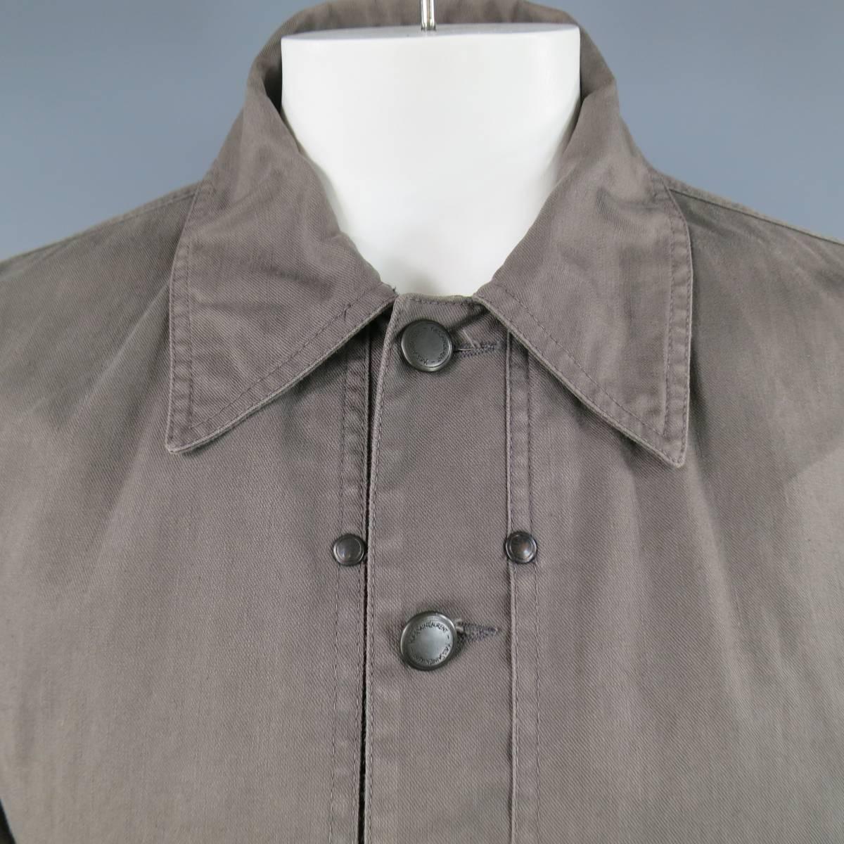 This rare YVES SAINT LAURENT trucker style jacket comes in a light weight taupe gray cotton denim and features a pointed collar engraved gunmetal tone buttons, work wear inspired overlay pocket panels, internal panel closure, and back tabs. Made in