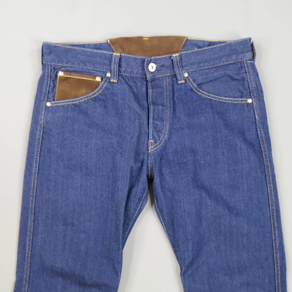 These JUNYA WATANABE MAN jeans come in indigo blue cotton denim and feature a tapered leg, button fly, vegan brown suede frontal pocket and matching back belt panel, and olive green canvas utility zip pockets on back. Made in Japan.
 
Excellent