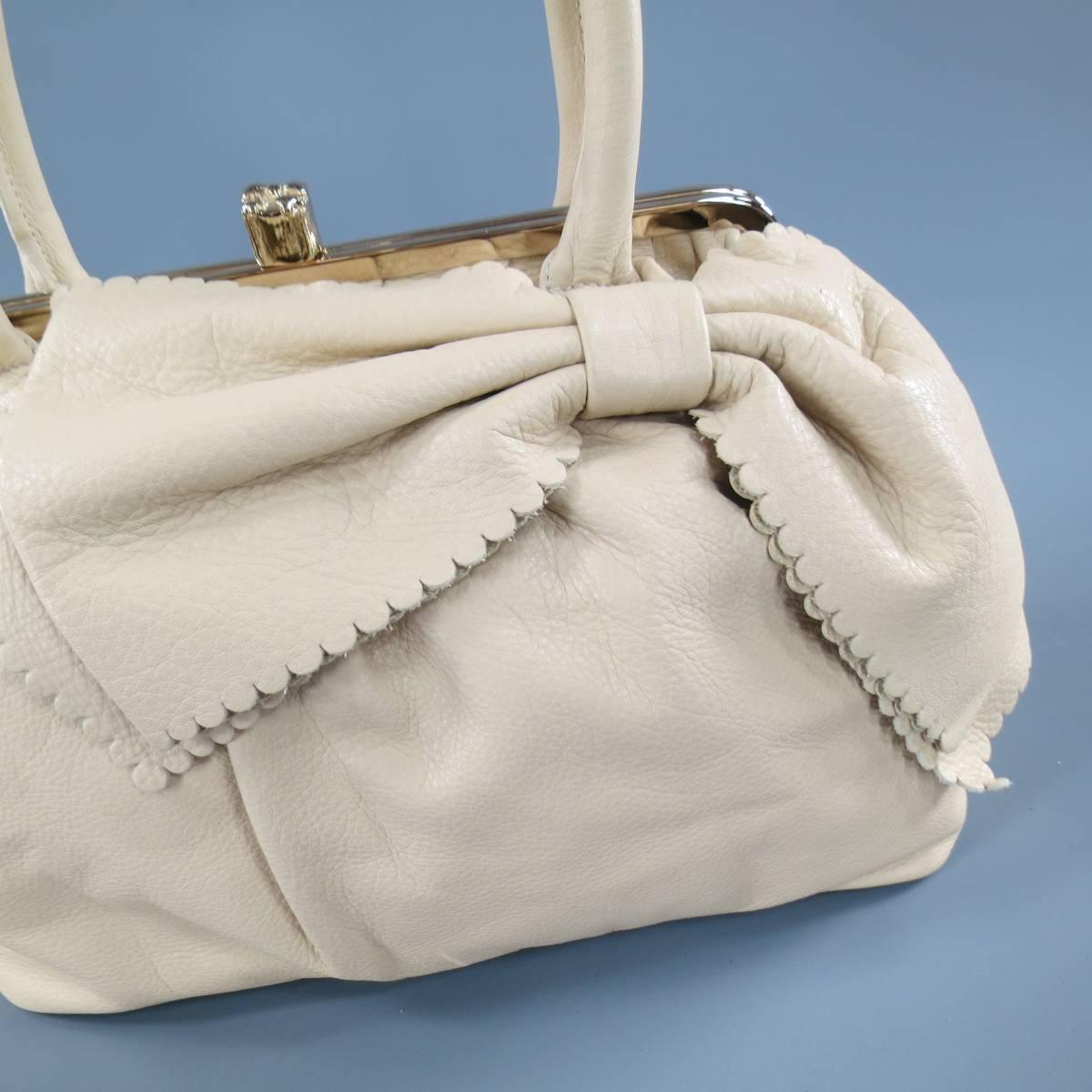 This lovely RED by VALENTINO purse comes in soft beige leather with a pleated top, oversized scalloped bow applique, gold tone hinge closure, leather top handles, and pink liner. With dust bag and tags. Circa 2012. Retails at $695.00.
 
Excellent