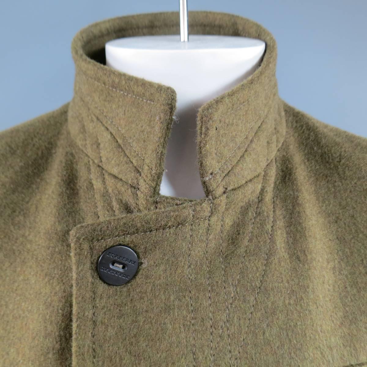This military style coat from BURBERRY comes in a heavy olive green wool flannel with hints of brown Heather and features a high neck, black engraved buttons, patch flap pockets with applique panel details, and back band detail. Made in Italy.
