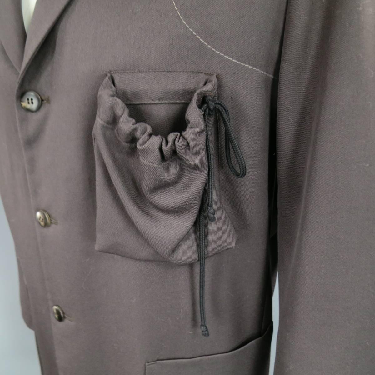 This unique GIULIANO FUJIWARA oversized sport coat comes in an ash brown wool twill and features a notch lapel, three button closure, double patch pockets, contrast stitch details n shoulders and elbows, and drawstring patch pocket on the chest.