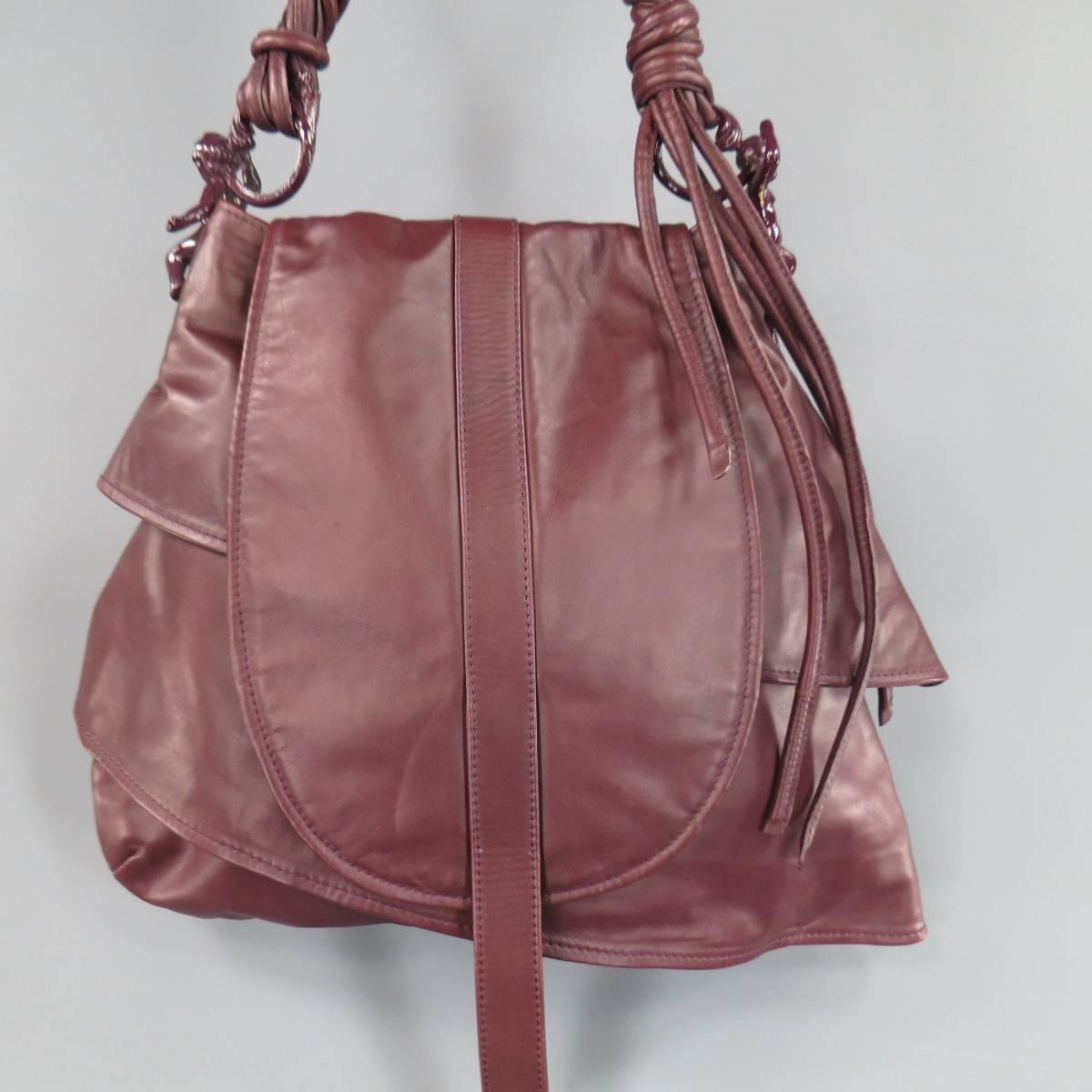 This fabulous ARNOLDO BATTOIS 2011-12 collection shoulder bag comes in a plum burgundy smooth leather and features a wrapped leather shoulder strap with fringe, enamel cherub hardware, layered body, and flap with extended strap. Made in