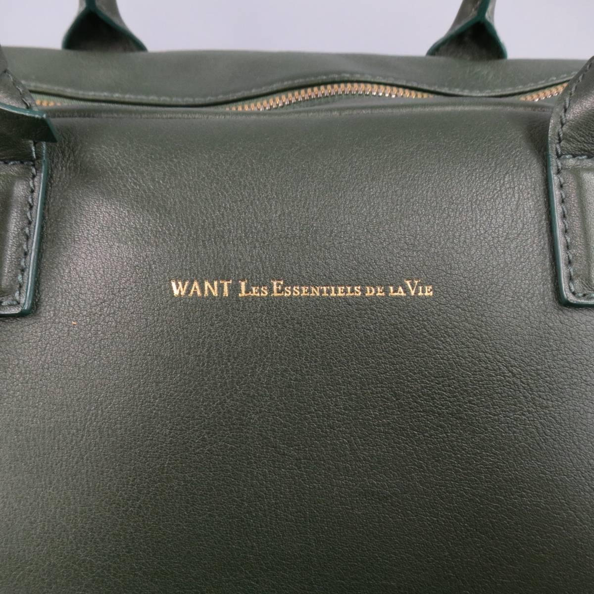 Classic duffle bag by WANT LES ESSENTIELS DE LA VIE in hunter green smooth leather featuring double top handles, gold metallic logo, silver and gold top zip closure, and detachable shoulder strap. Wear throughout leather and hole in shoulder strap.