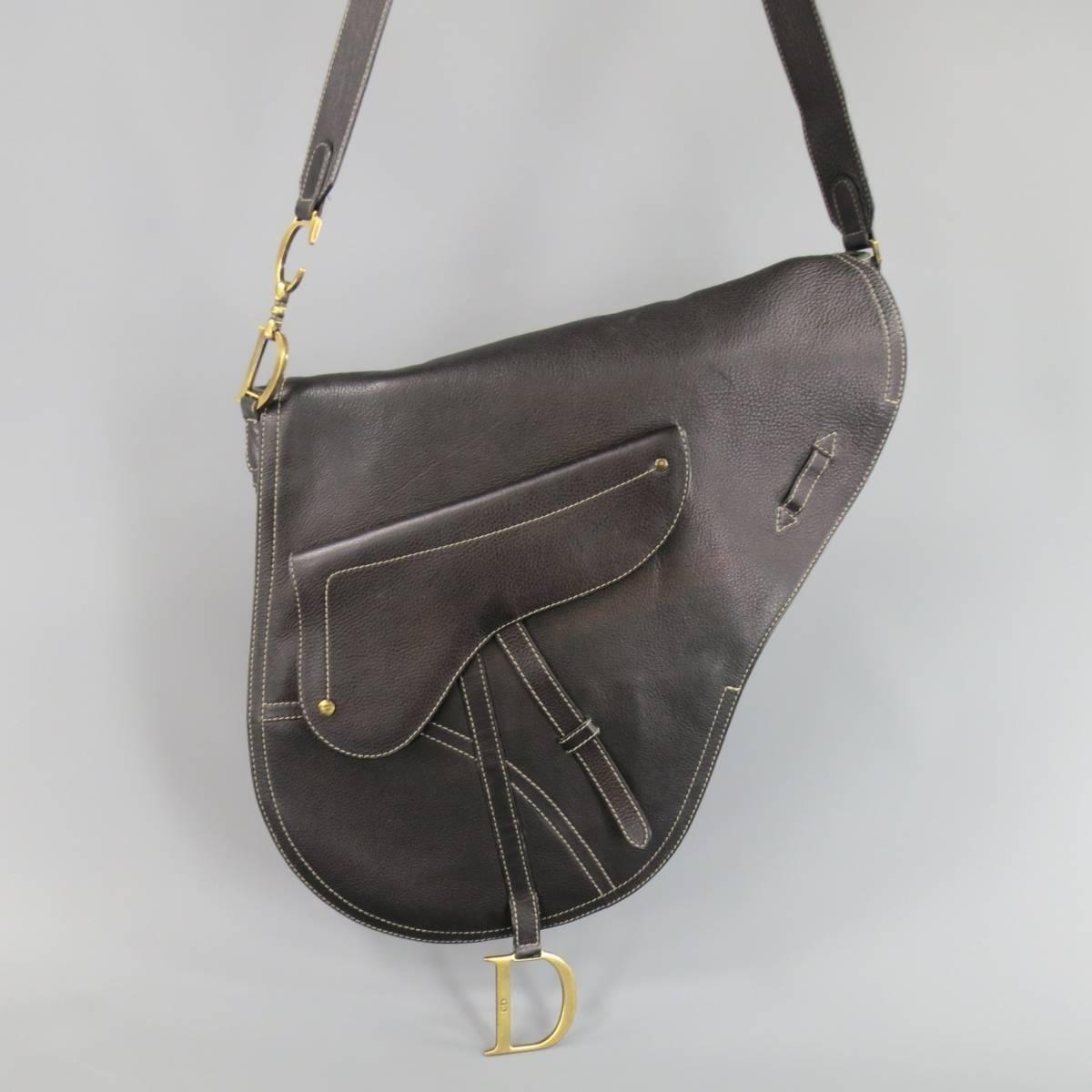 Iconic CHRISTIAN DIOR large crossbody saddle bag in deep brown black leather with contrast stitching, frontal snap pocket, dark gold tone engraved D charm, adjustable shoulder strap with oversized 