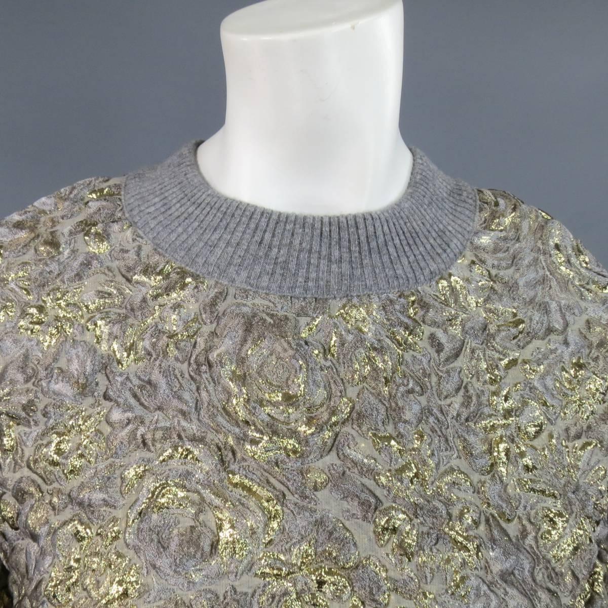 This fabulous DOLCE & GABBANA dress comes in a beautiful gray and gold metallic floral textured jacquard fabric and features a ribbed knit crewneck, oversized silhouette, and three quarter puff sleeves. Made in Italy.
 
Excellent Pre-Owned