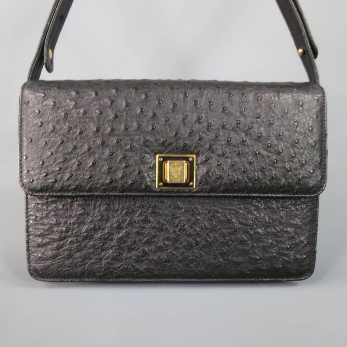 This fabulous and rare vintage GUCCI handbag comes in semi matte black ostrich textured leather and features a classic structured rectangle shape, flap closure with gold tone crest logo engraved twist closure, leather interior, and adjustable