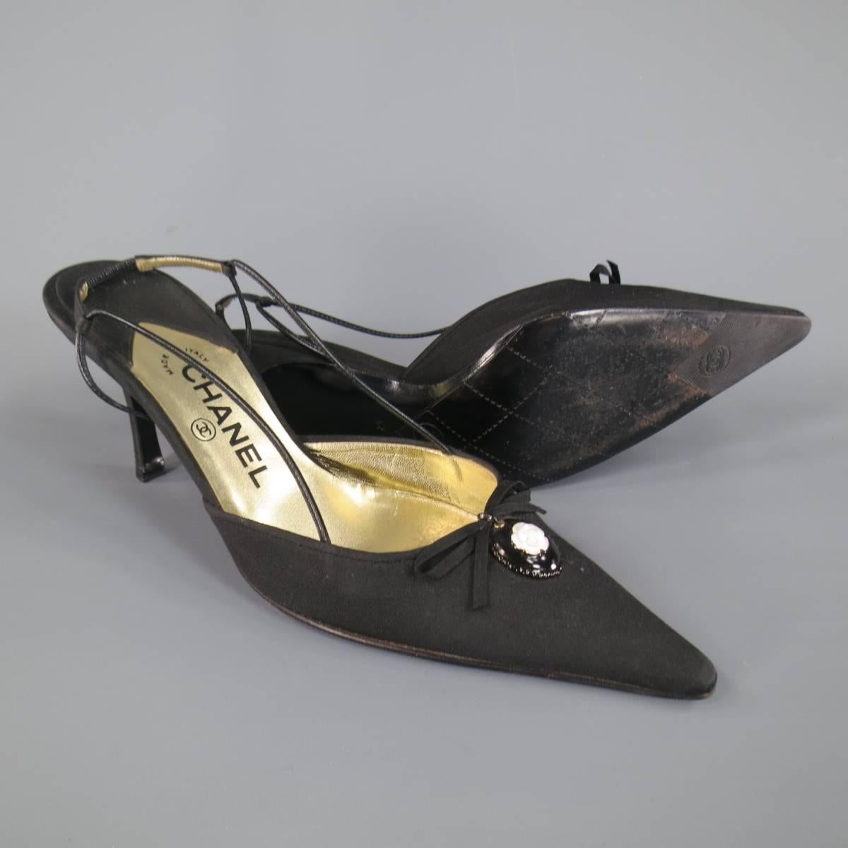 These classic CHANEL pumps come in black silk Tafeta and feature a skinny strap ankle harness slingback, covered stiletto heel, and pointed toe with bow and black and white logo camellia  embellishment. Wear throughout fabric. Made in Italy.
