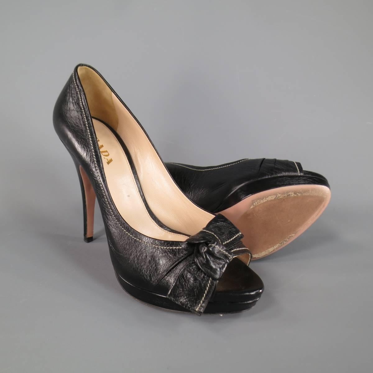 Fabulous PRADA pumps in black leather with a peep toe, covered stiletto heel, low platform, contrast stitching, and knotted bow detail. Made in Italy.
 
Excellent Pre-Owned Condition.
Marked: IT 39
 
Heel: 4.75 in.
Platform: 0.75 in.
