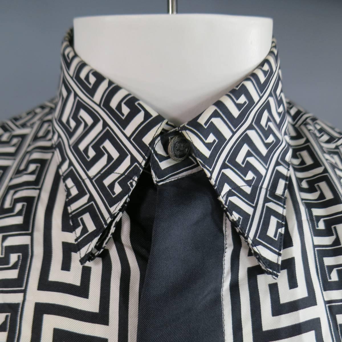 La chemise à manches longues VINTAGE VERSACE CLASSIC V2 se compose d'une matière en soie dans un ton noir et blanc. Conçu avec un devant boutonné, un col pointu à double épaisseur et une patte de boutonnage cachée. Il est agrémenté d'une bordure