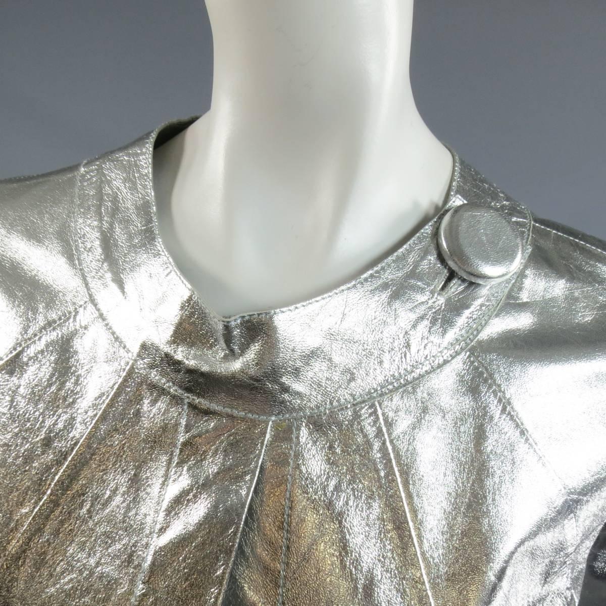 This fabulous 1960's inspired Glen Arthur for CHESTER jacket comes in a light weight metallic silver leather and features a round neckline with single covered button closure, A-line silhouette, open front, back pleat, and gorgeous laser cut floral