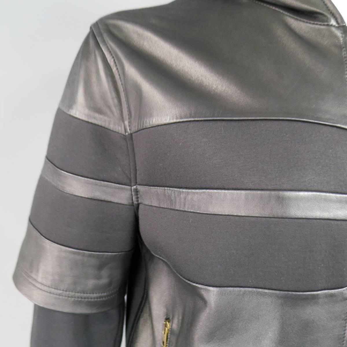 This rare GIVENCHY hoodie comes in black cotton jersey and features a short sleeved neoprene and leather striped patchwork over layer, ribbed waistband, dark gold tone zip front, double zip pockets, signature T stitch, and leather hood. Made in