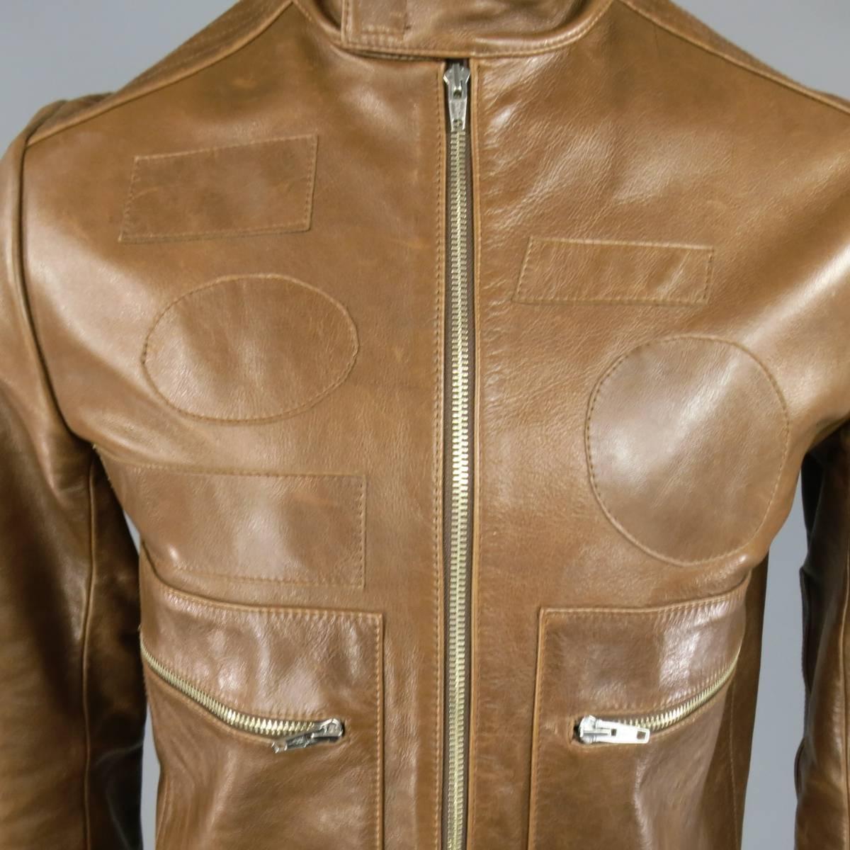 This awesome motorcycle jacket comes in a structured light brown leather and features a stand up collar with velcro closure, zip up front, quilted elbow patches, zip velcro cuffs, double zip patch pockets, and various blank tone on tone patches