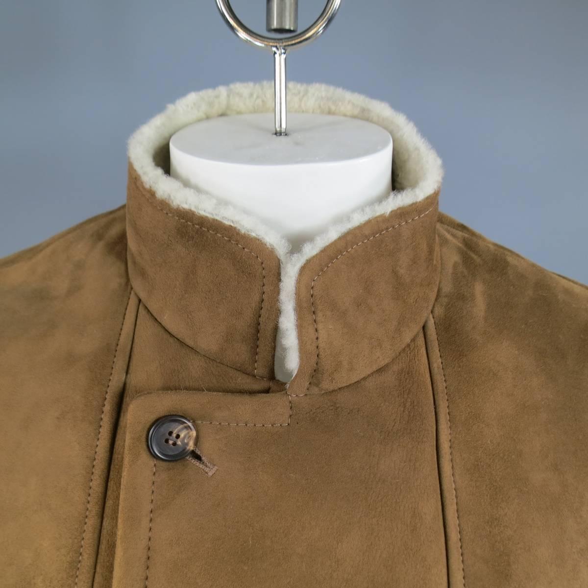 This classic BRUNELLO CUCINELLI winter coat comes in a soft tan shearling lined suede and features a double breasted button up closure, high collar, vertical and flap pockets. Minor wear throughout. Made in Italy.

Retails at $6995.00.

Good