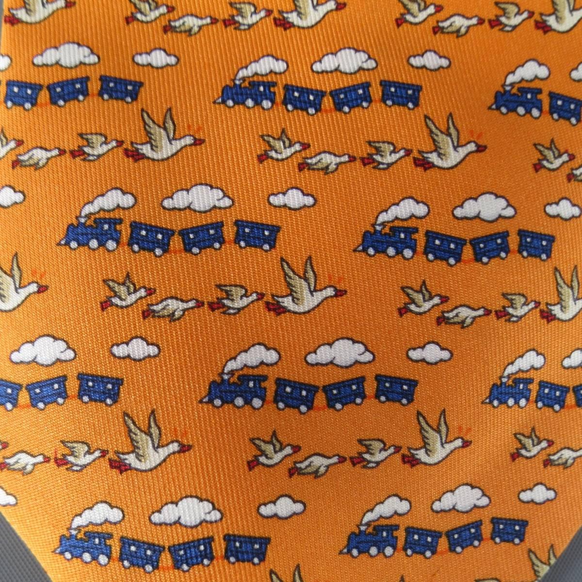 HERMES Tie consists of 100% silk material in a vibrant orange color tone. Designed in a slim style, graphic print throughout body. Detailed with birds, clouds and trains in beige, blue and white tones. Made in France.
 
Good Pre-Owned