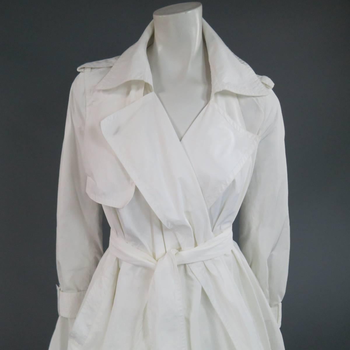 This chic minimalist KAUFMAN FRANCO trench coat comes in a textured off white polyester and features a pointed lapel, epaulets, storm flap, belted cuffs, A line wrap skirt, and thick belt with tan leather ends.
 
Good Pre-Owned Condition.
Marked: