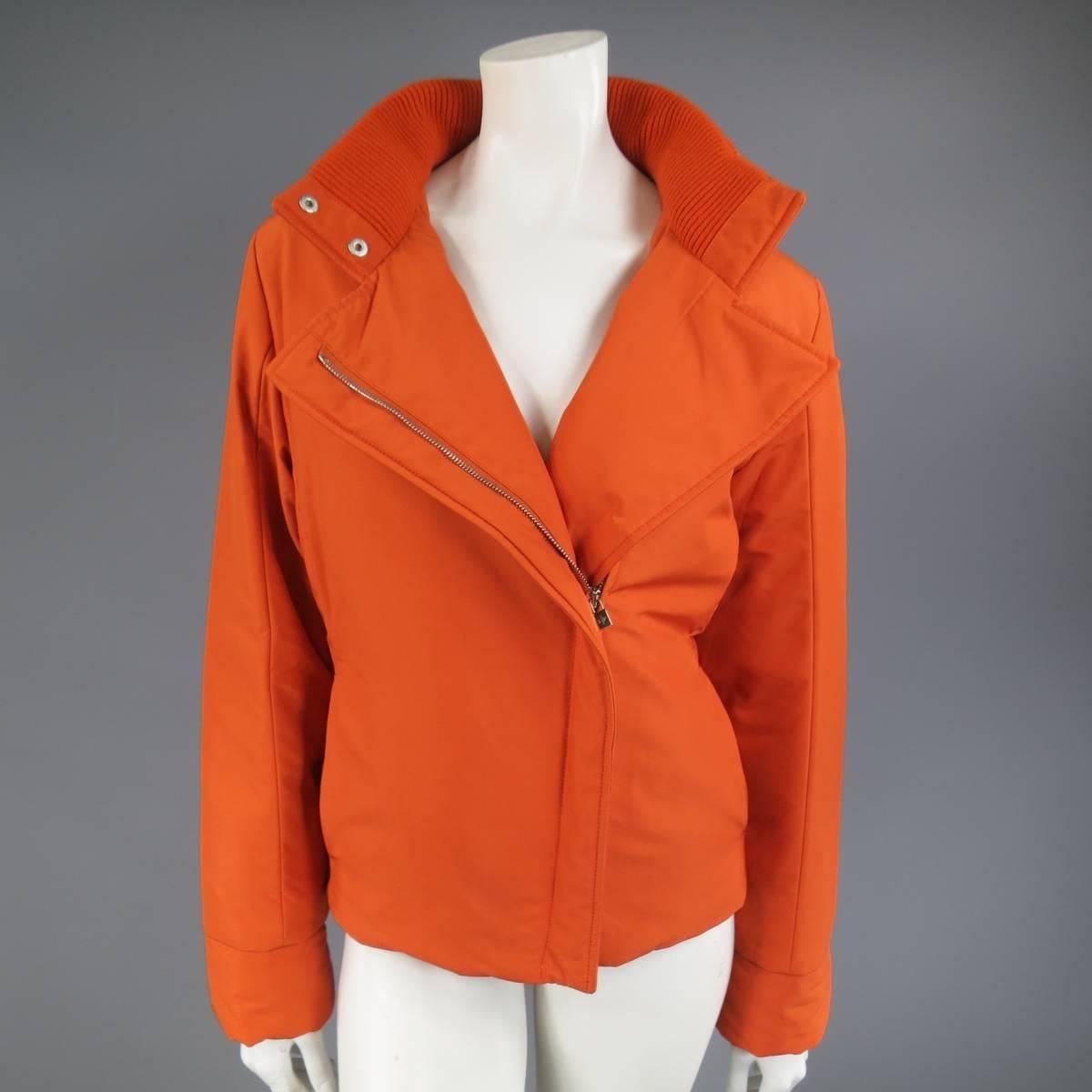 This classic LORO PIANA Storm System ski jacket comes in an orange polyester blend and features a high stand up snap collar with ribbed liner, detachable zip off hood, slit pockets, slanted hidden zip closure, and green satin padded liner. Made in