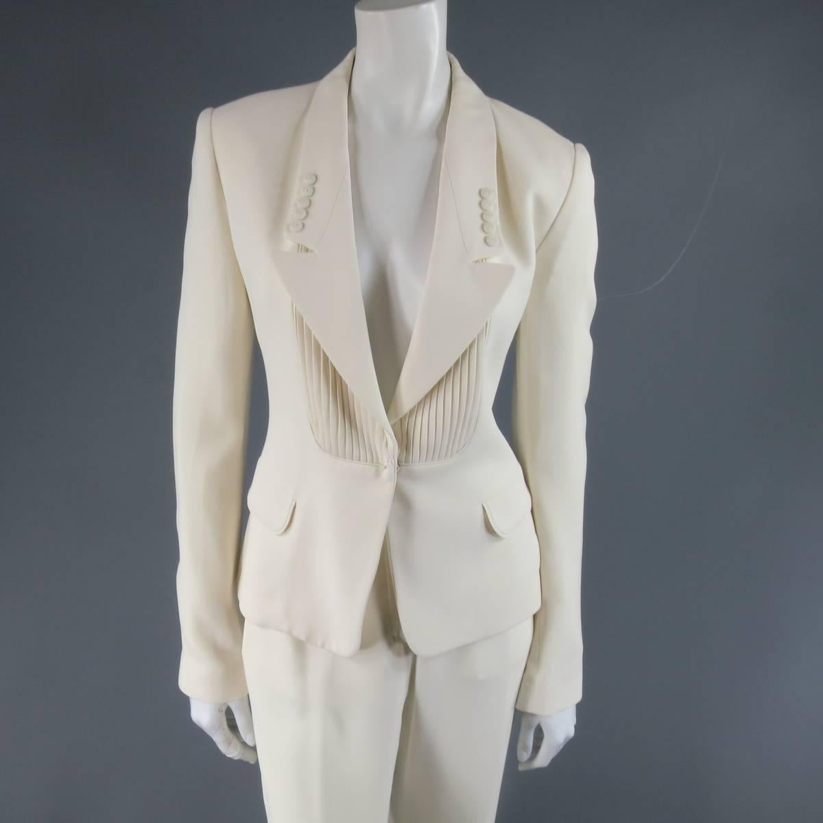 This gorgeous VIKTOR & ROLF tuxedo suit comes in a creamy off white matte silk crepe features a cropped jacket with a pointed button detailed lapel, hidden snap closure, and pleated bib with matching pleated waistband straight leg trousers. Very