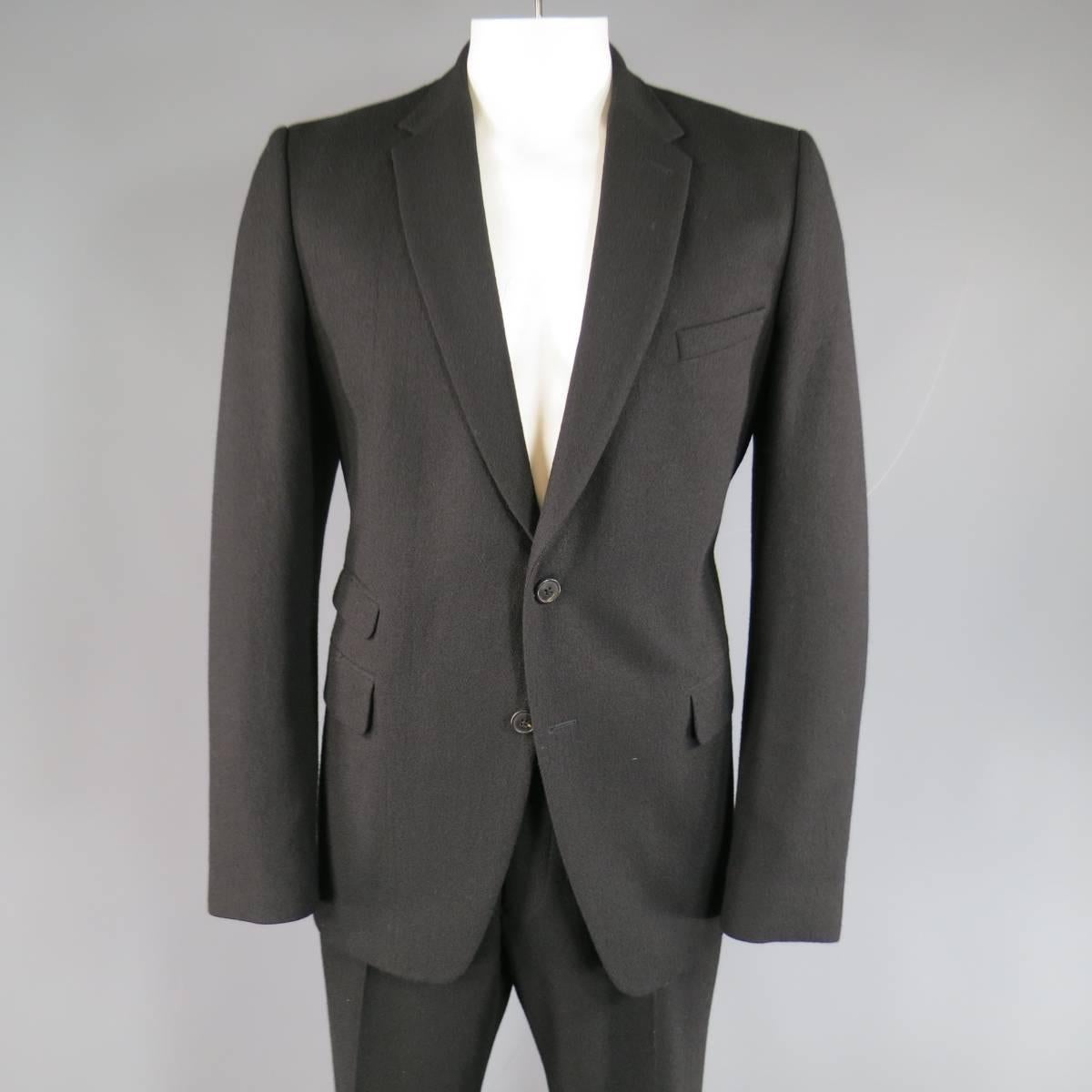 Classic winter suit by DRIES VAN NOTEN in a black wool felt featuring a notch lapel, two button sport coat with triple flap pockets and single vented back. Includes matching tailored, flat front trousers.
 
Excellent Pre-Owned Condition.
Marked: