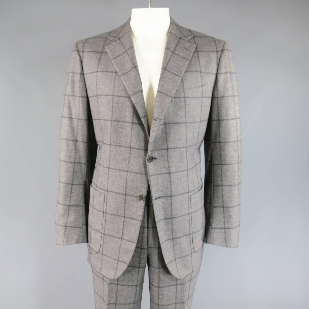 This chic KITON suit comes in a light gray and charcoal Windowpane print cashmere and includes a notch lapel, functional button sleeve, double vented , three button sport coat with patch pockets and matching flat front, cuffed dress pants. Small