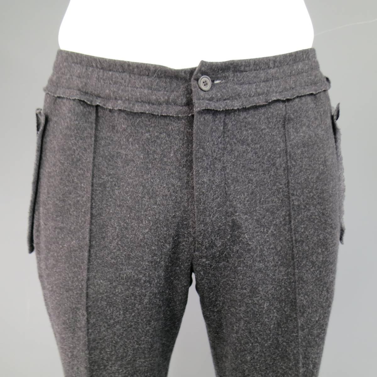LANVIN trousers in a charcoal Heather gray stretch wool flannel features an elastic, waistband with internal drawstring, stitched flat front, raw edge reverse seam sides, and slit pockets with raw edge appliques.
 
Excellent Pre-Owned
