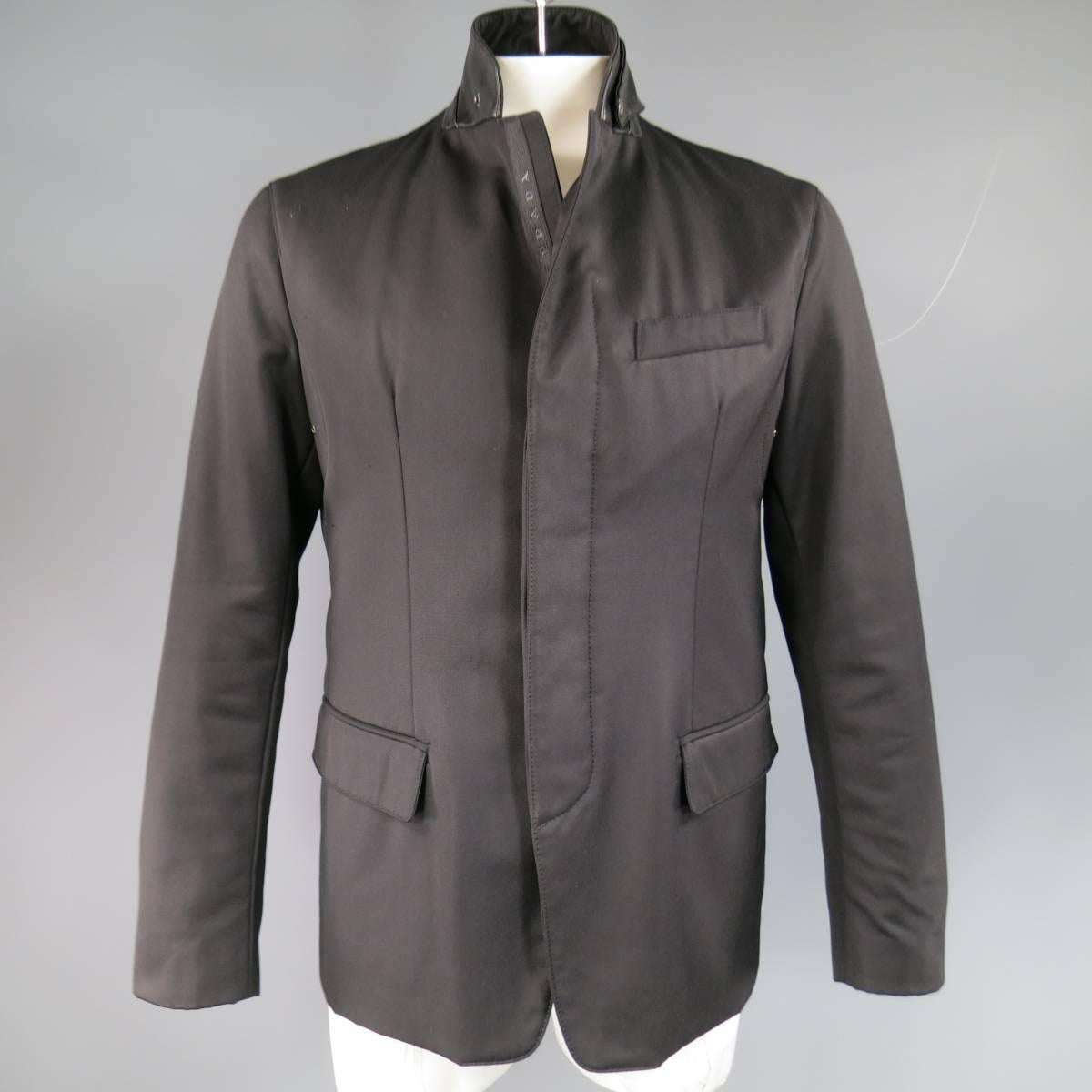 This unique PRADA sport coat comes in a lightly padded polyester twill and features a notch lapel, leather lined collar with snap storm flap, hidden placket button and zip closure, double flap pockets, and underarm grommet vents. Made in Italy.
